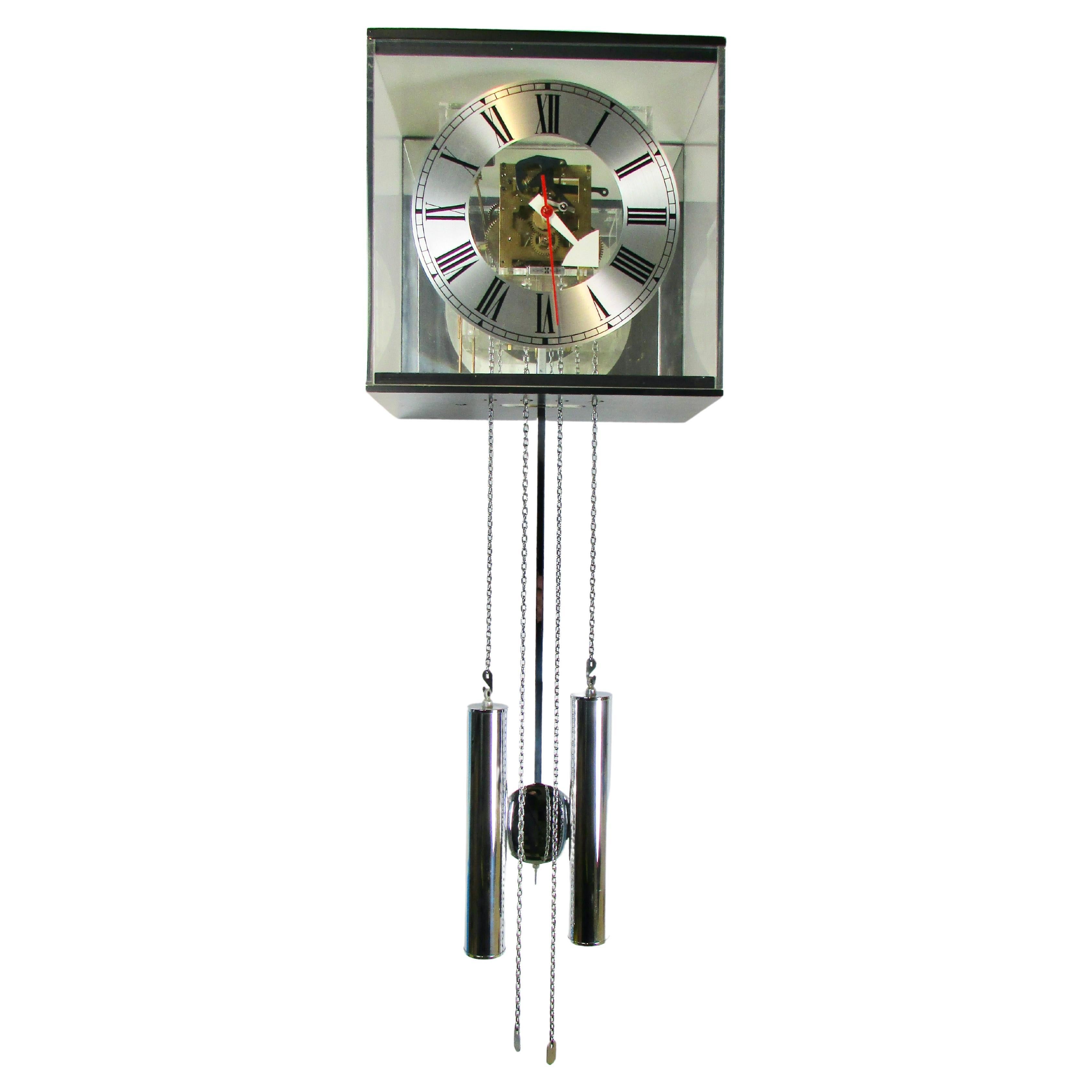 Modernist take on a kind of deconstructed grandfather clock look. Lucite case allows internal works to be part of the design. Eight day weights, chains and pendulum in chrome. Clock has charming chimes on the hour and once at half past. 
Arthur