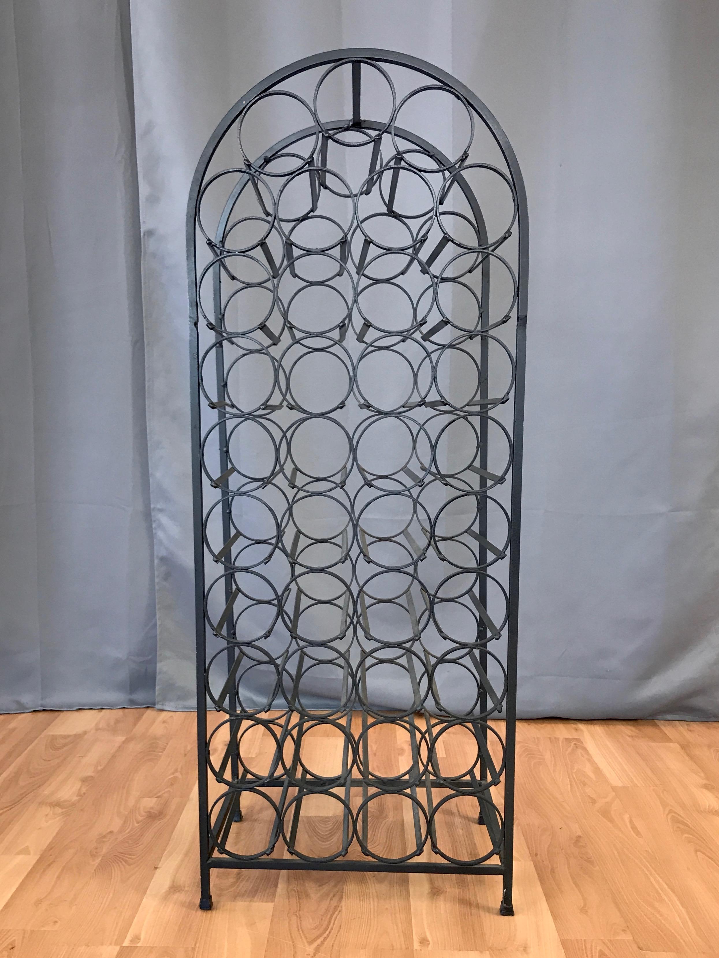 A late 1960s 39-bottle wrought iron wine rack by Arthur Umanoff, originally offered by Boyeur Scott Furniture Co., and later by Shaver Howard.

Heavy arched frame nicely echoes the body of a wine bottle, and neatly contains 39 slots with hooped