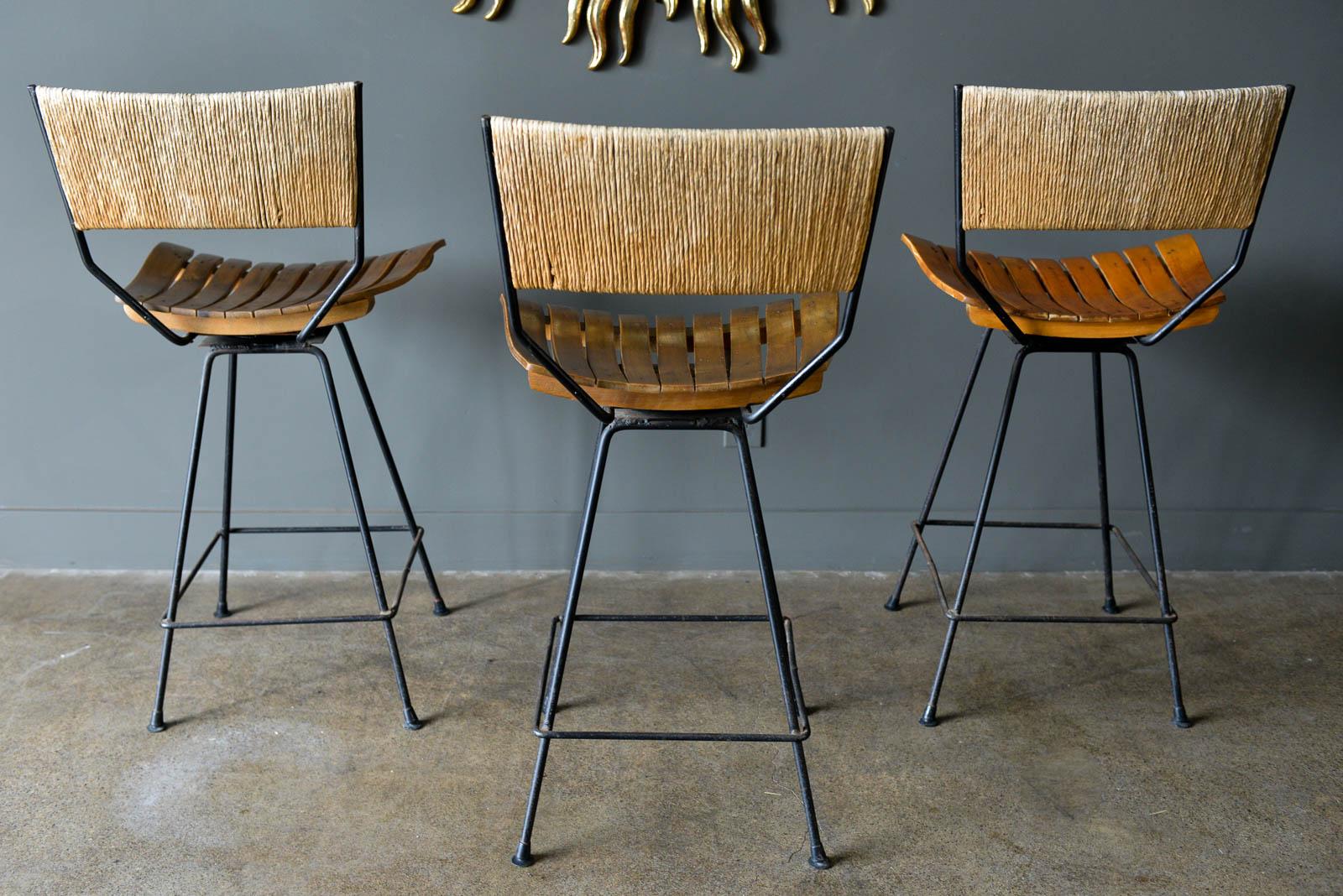 Arthur Umanoff iron and slatted wood barstools, circa 1965. Swivel seats rotate 360 degrees smoothly. Iron has some patina on the legs. Original floor protectors. Counter height stools, seats measure: 26