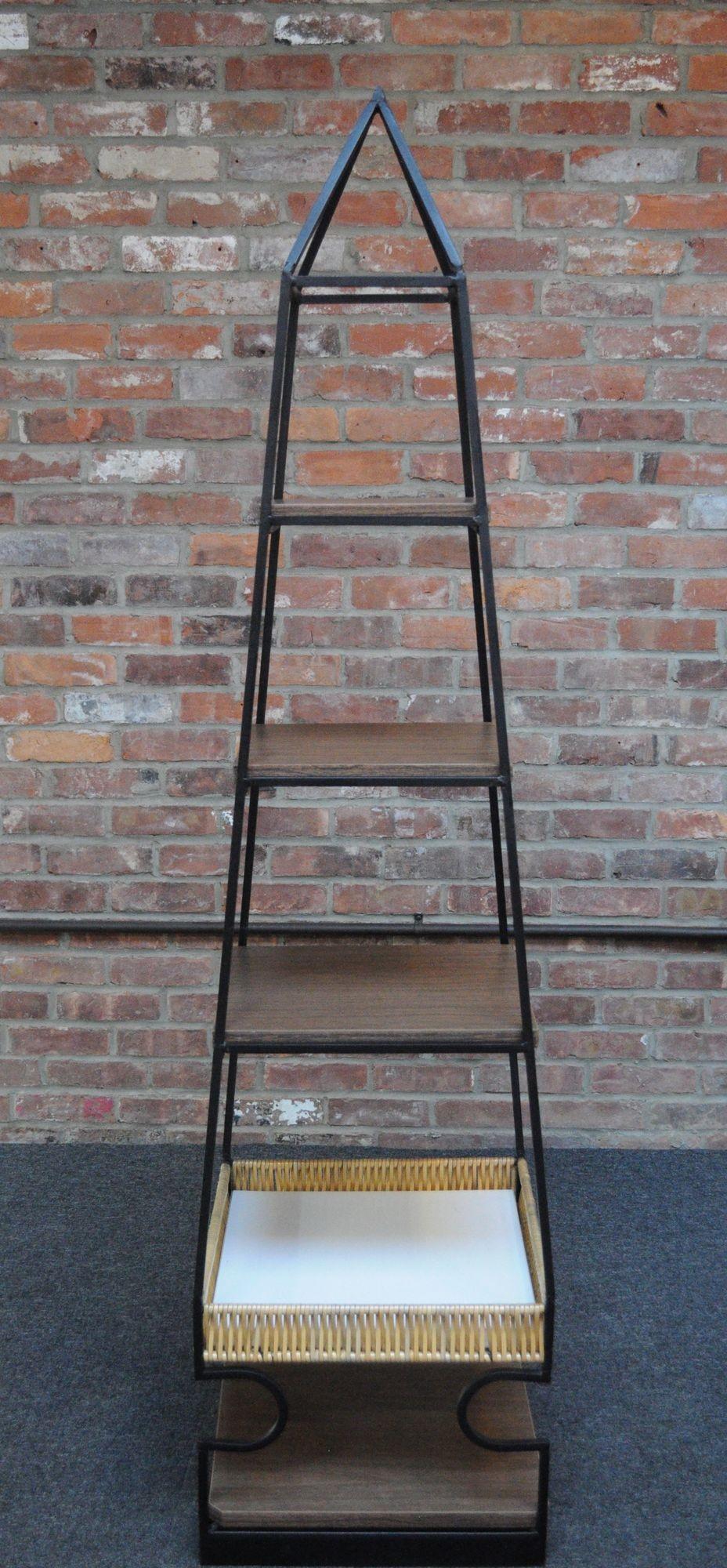 Scarcely seen sculptural wrought iron shelving unit designed by Arthur Umanoff for Shaver Howard.
Unique, graceful pyramid/obelisk-form with four rectangular shelves in faux wood grain laminated pressboard and a rattan basket. Shelves are mounted by