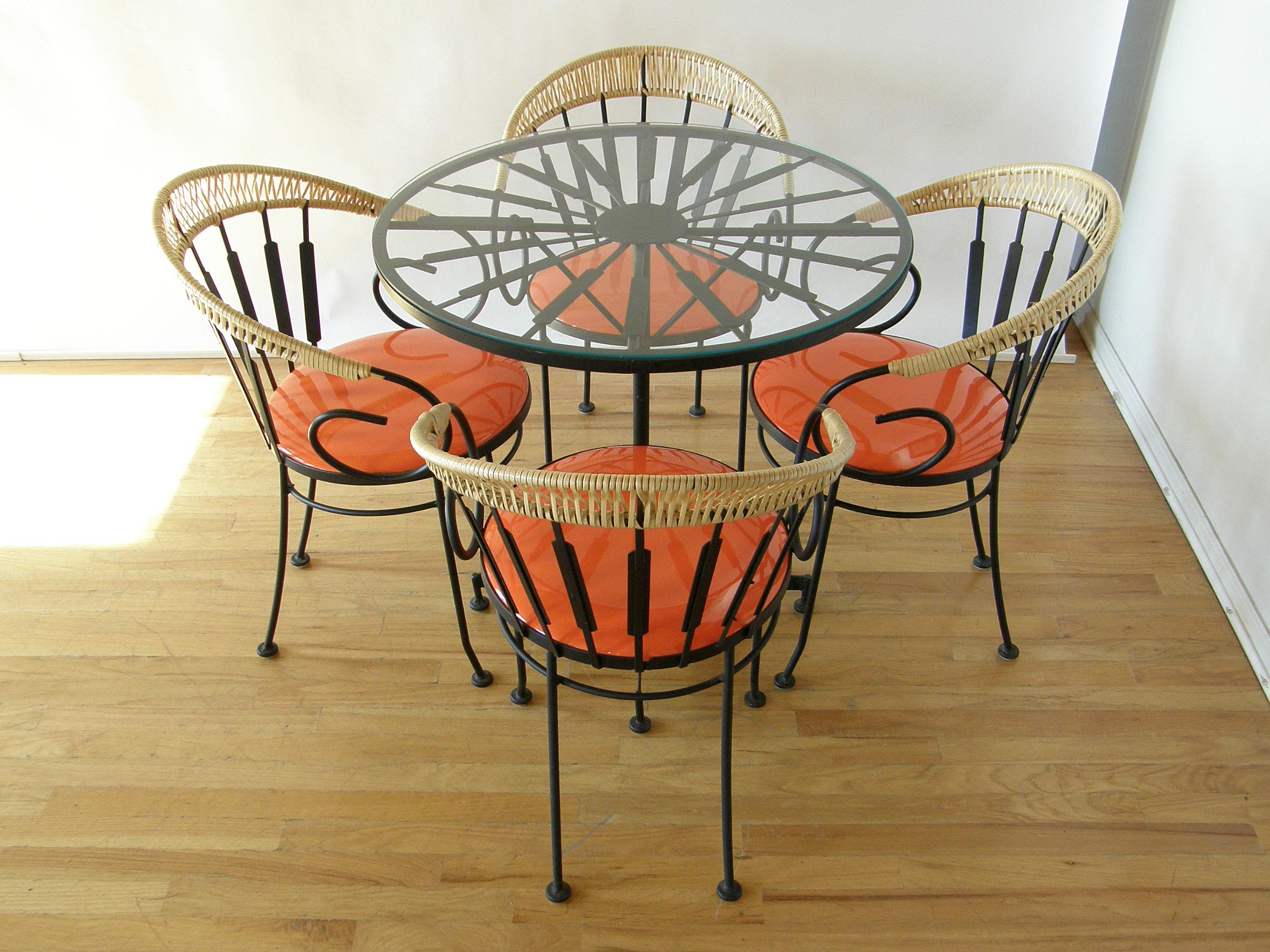 This festive dinette set was designed by Arthur Umanoff for Shaver Howard. The frames are wrought iron, and the table and chairs all have an abstract, feather-like detail. They form a kind of sunburst effect on the table underneath the glass top. On