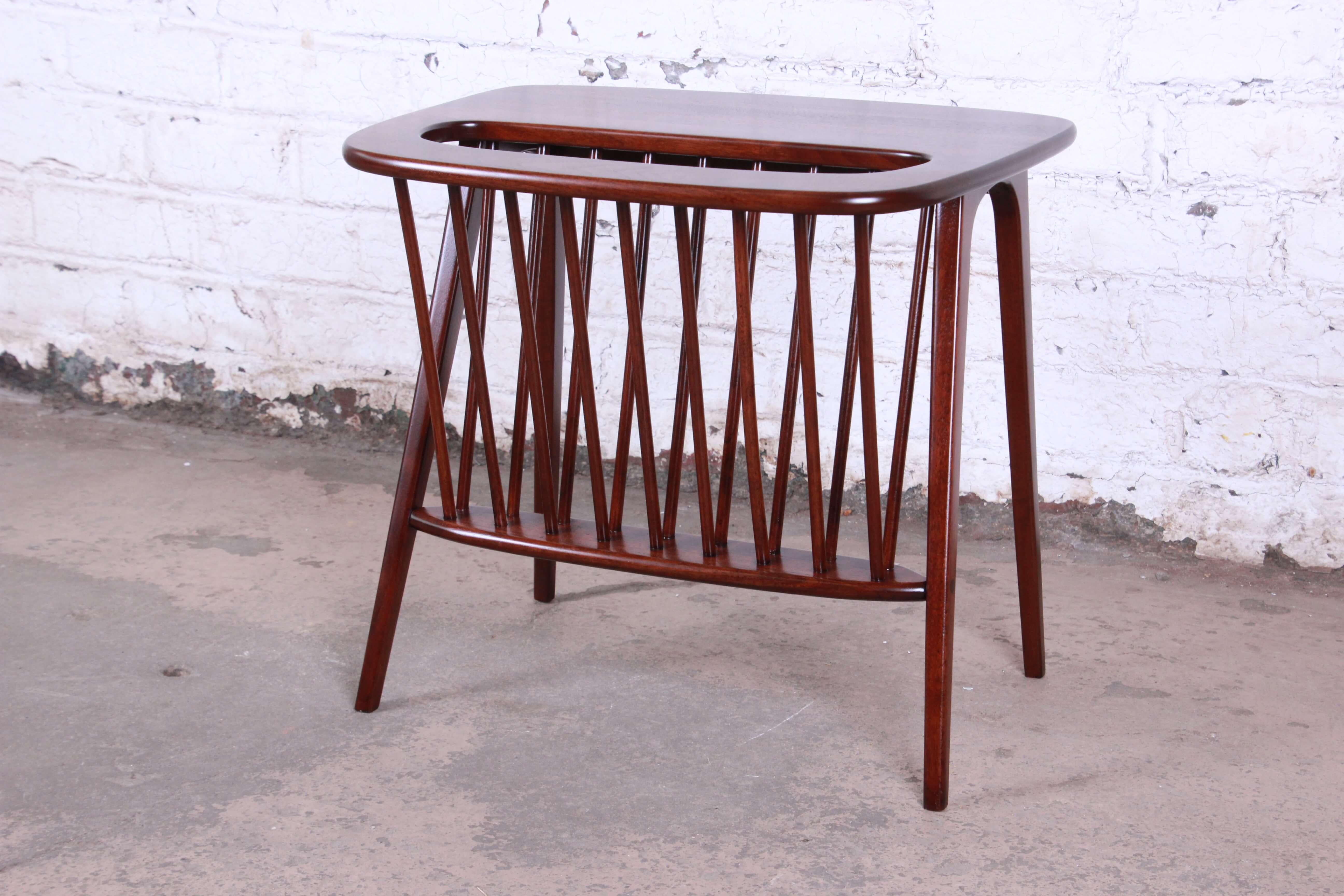 Offering a very sleek solid walnut magazine rack or side table by Arthur Umanoff. The rack has been newly refinished and offers a nice sized slot for magazines or other items with a small area to act as a table top. This piece has sleep Mid-Century