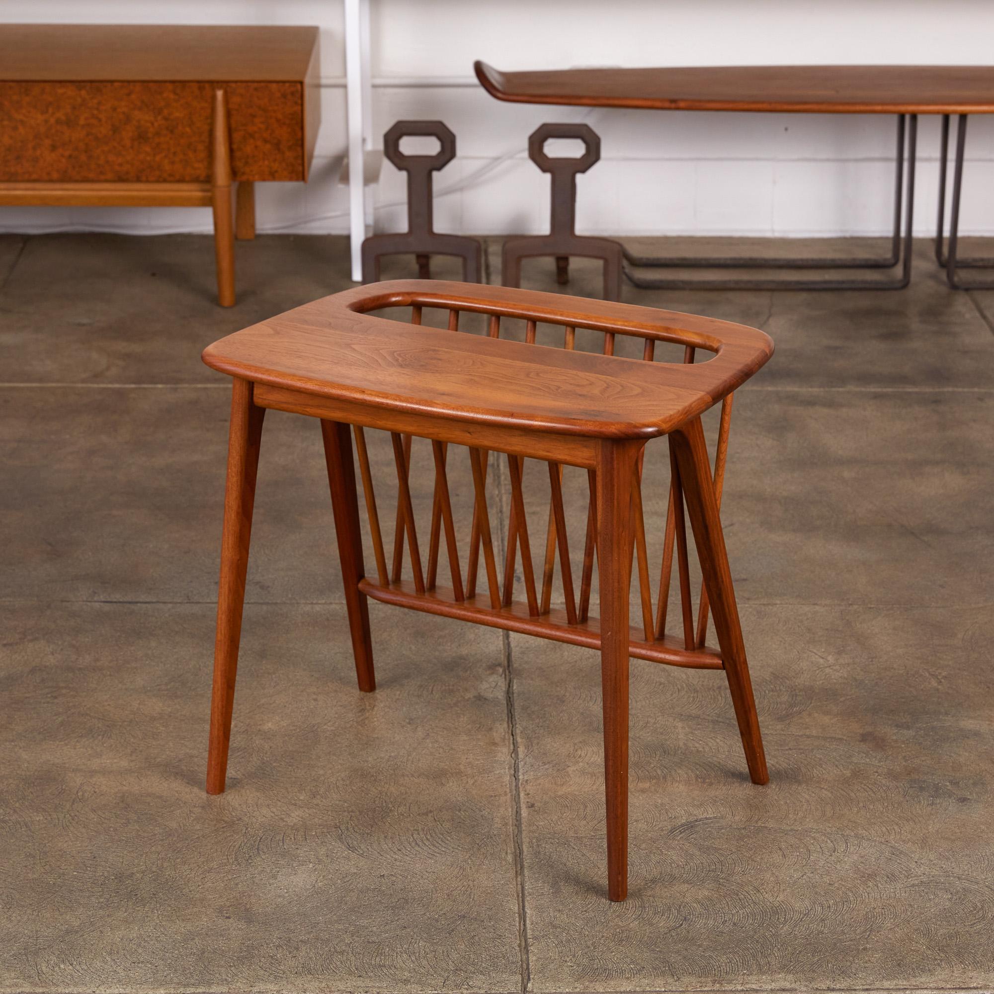 Walnut side table with magazine rack by Arthur Umanoff for Washington Woodcraft, USA, circa 1950s. The table features a sculpted solid walnut top and body with tapered legs and dowel joinery. The storage area is composed of two opposing rows of