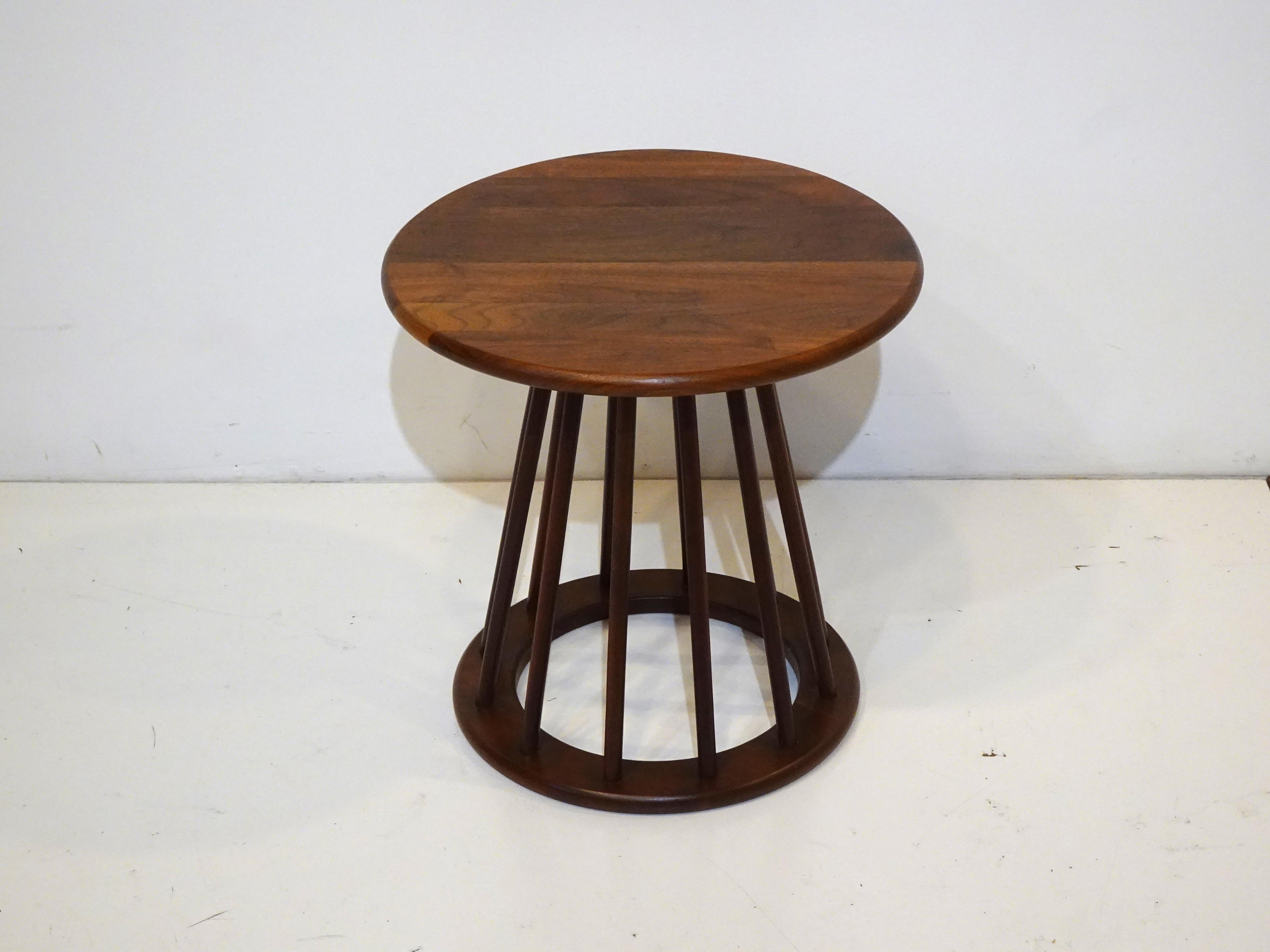 A well crafted solid walnut side table with round top and spindles running to the lower round ring walnut base. A light and airy design by Arthur Umanoff noted designer of many Mid Century forms and items from some of the biggest companies during