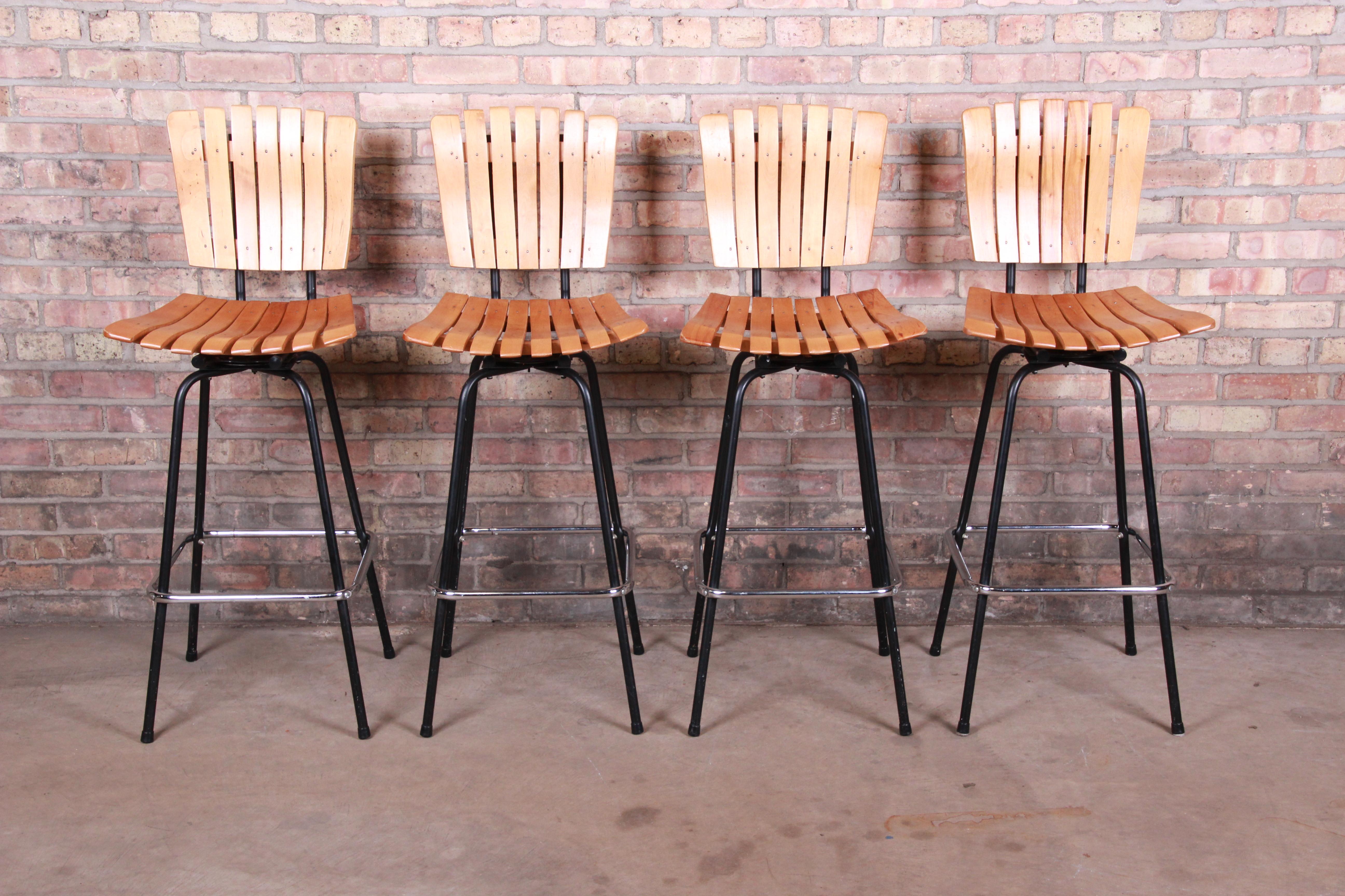 A gorgeous set of Mid-Century Modern swiveling bar stools

In the manner of Arthur Umanoff

USA, circa 1960s

Slatted wood seats and backs, with steel frames.

Measures: 17