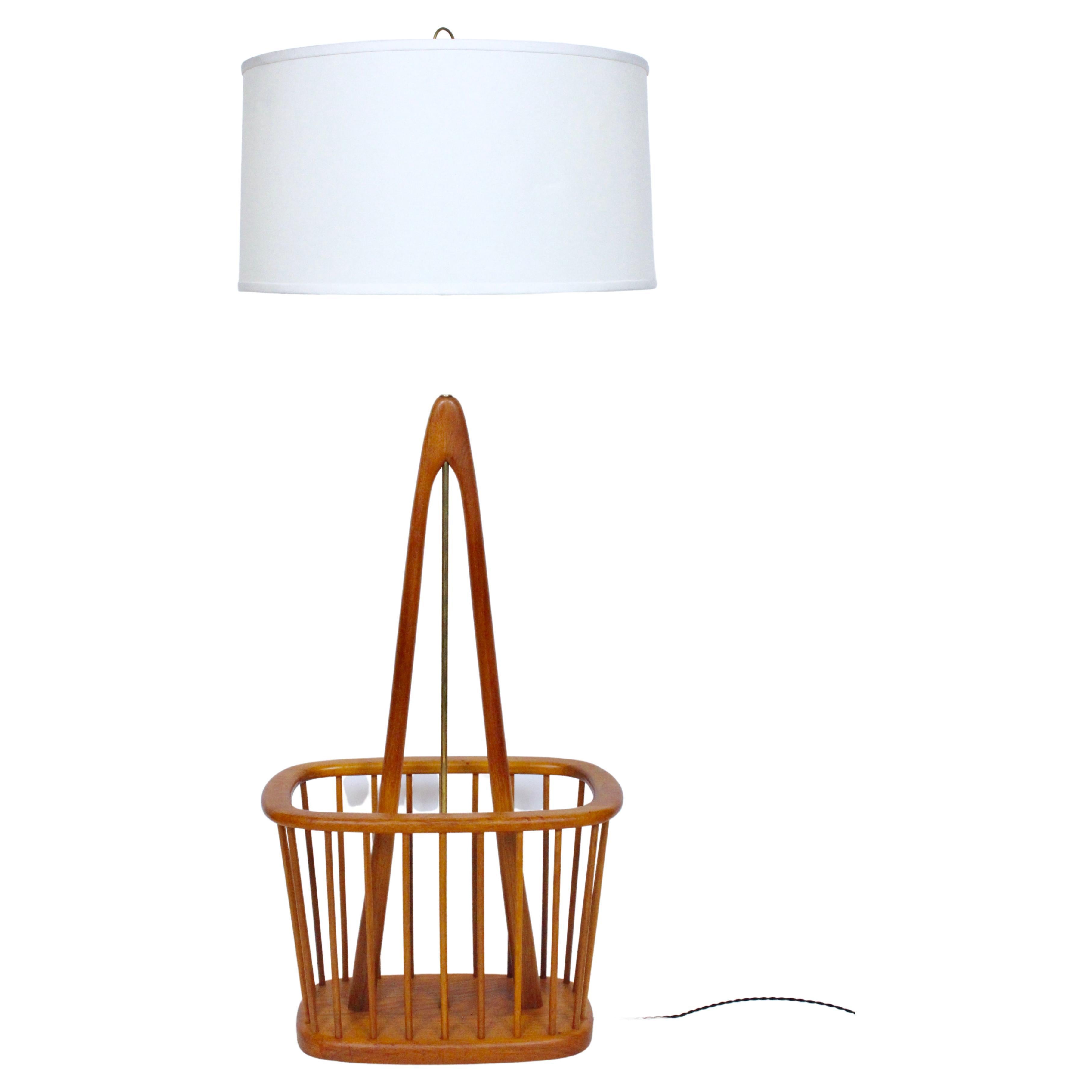 Sculptural Arthur Umanoff attributed teak and brass floor lamp. Featuring a turned Teak wishbone form,versatile oval rimmed (14H) Magazine Stand, turned teak spindle surround with Brass column and hardware. 47H to top of socket. Shade shown for
