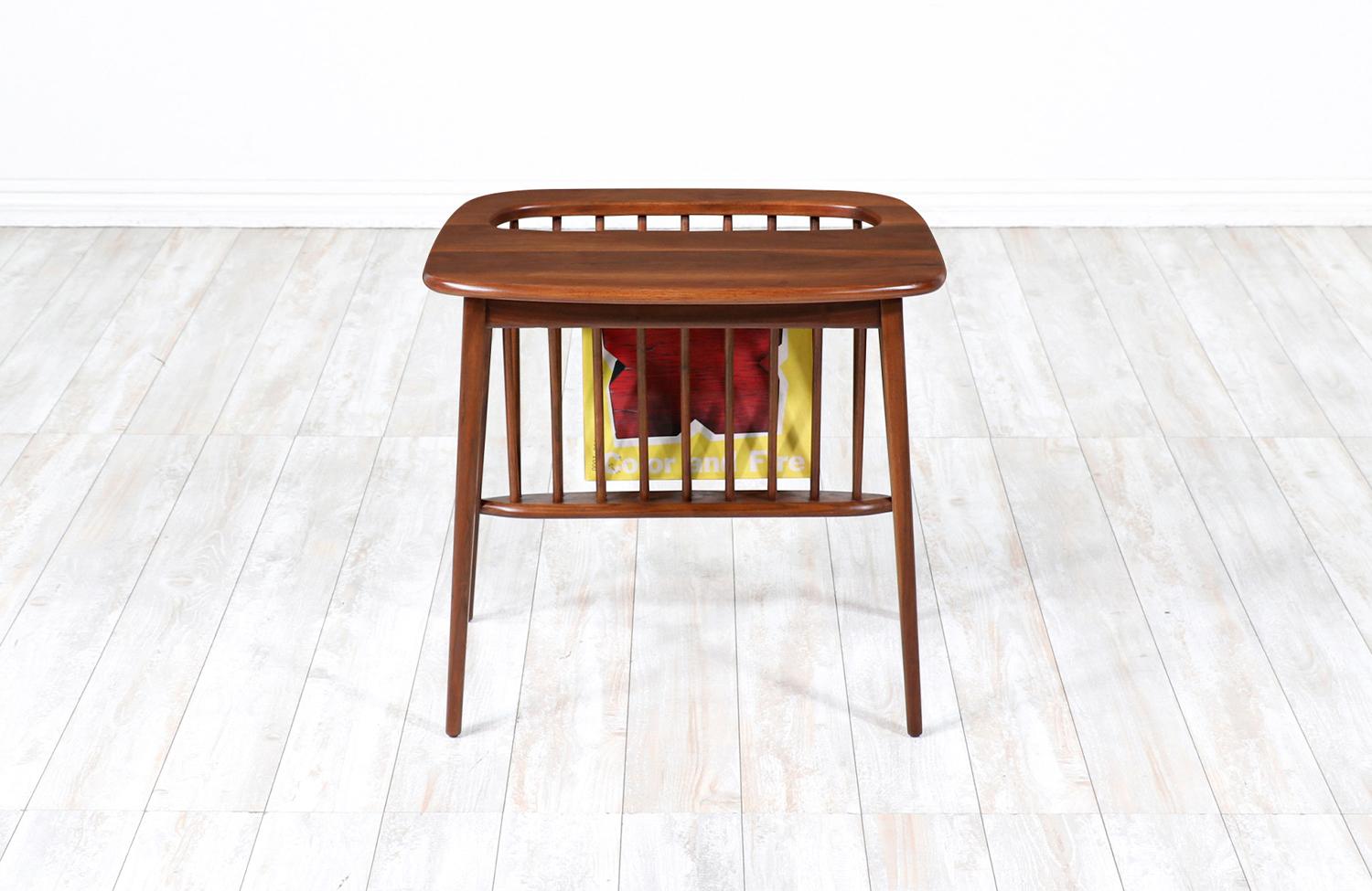 Modern magazine rack designed by Arthur Umanoff for Washington Woodcraft in the United States in 1964. This sleek and versatile side table design features a solid walnut wood structure with a slim magazine holder to conveniently store your reading