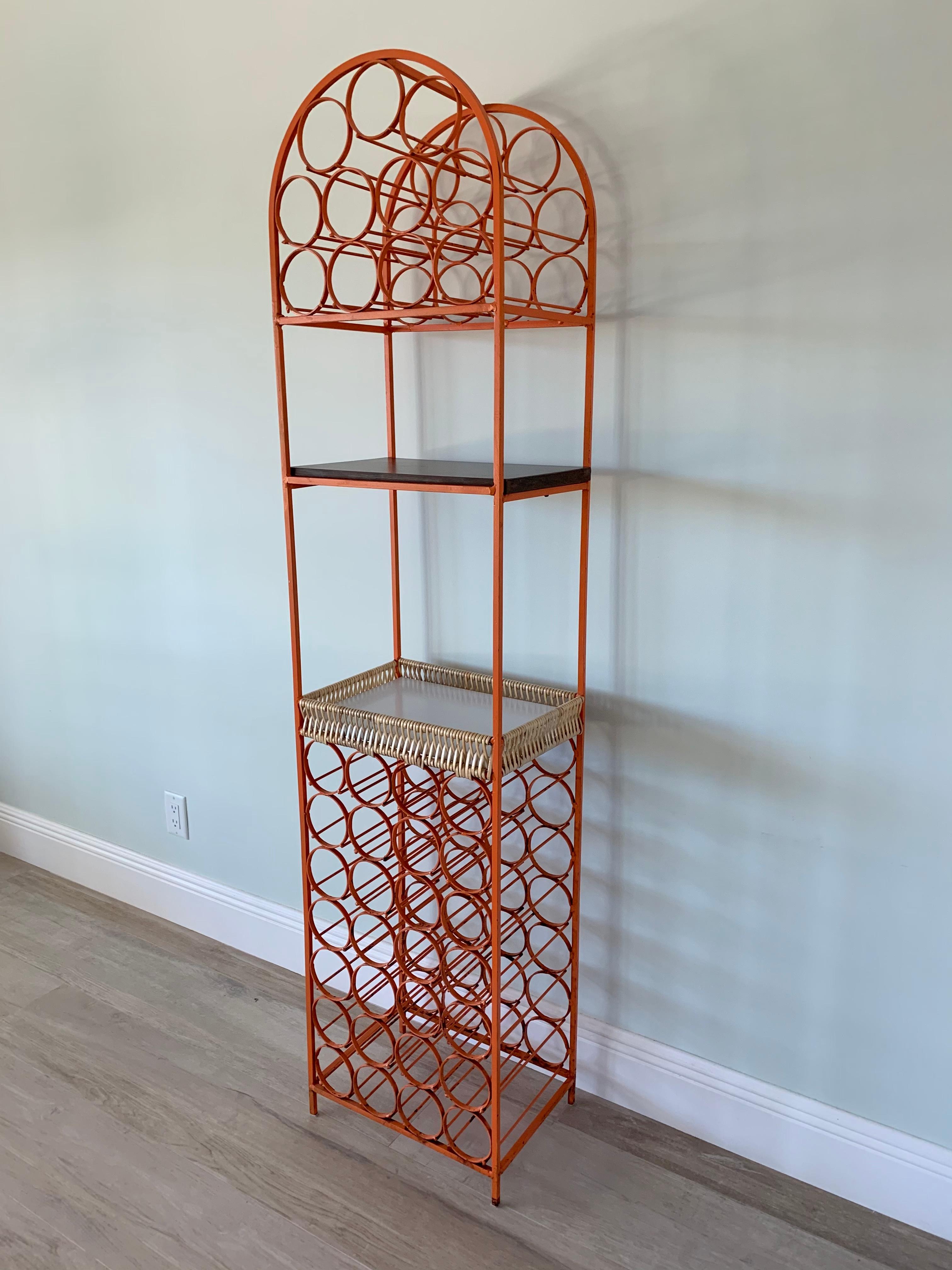 Orange wrought iron wine rack by Arthur Umanoff.
It can hold up to 39 bottles and includes a woven basket type shelf and a laminated shelf to hold glasses, serve drinks or even showcase you favorite bottles and bar utensils.
Manufactured for the