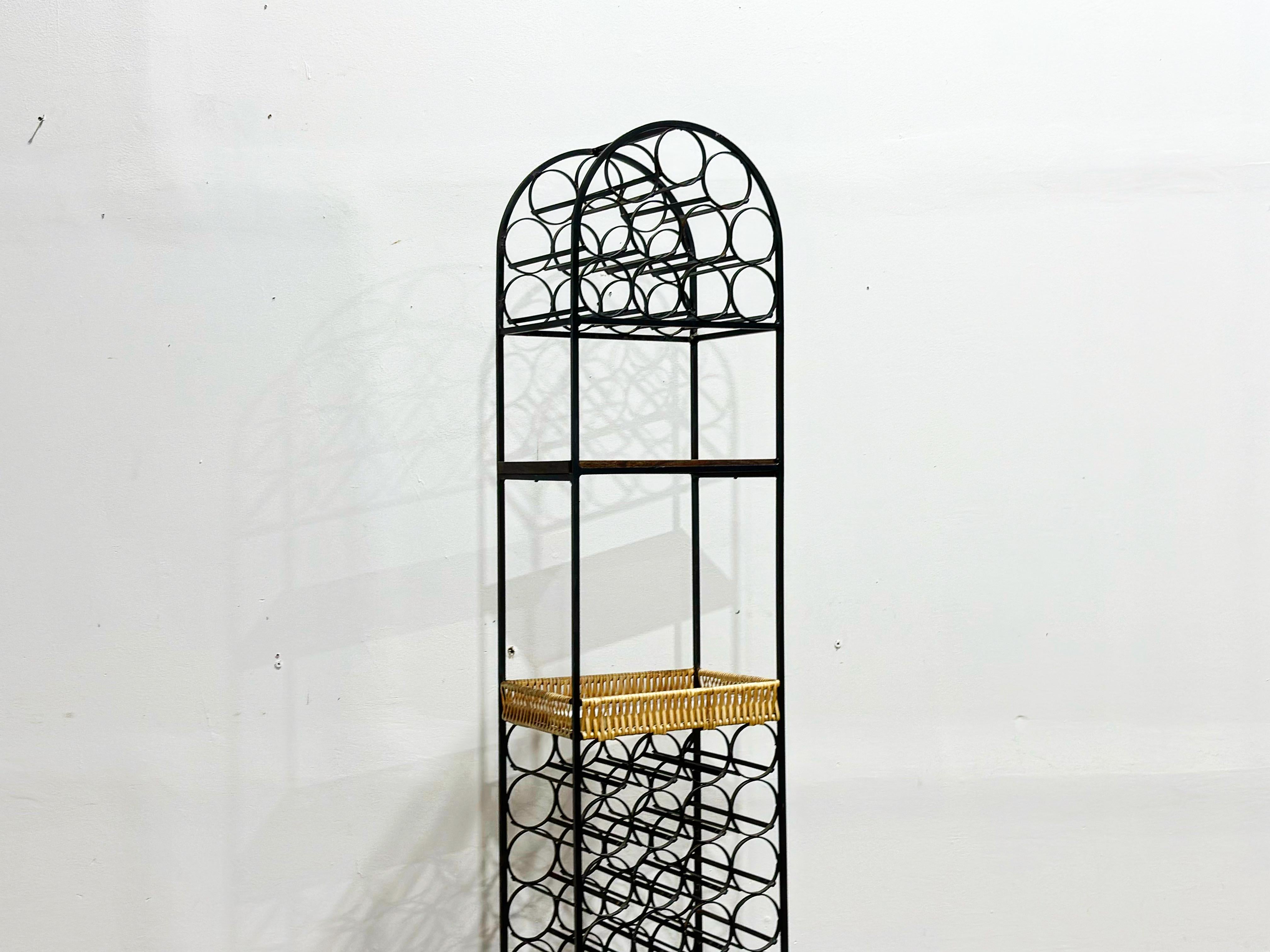 Wrought iron and rattan wine rack by Arthur Umanoff. Storage for 39 bottles - features a woven shelve type basket for you barware, glasses etc. One upper wood tone formica shelf for additional storage or work surface. Great for that tight spot in