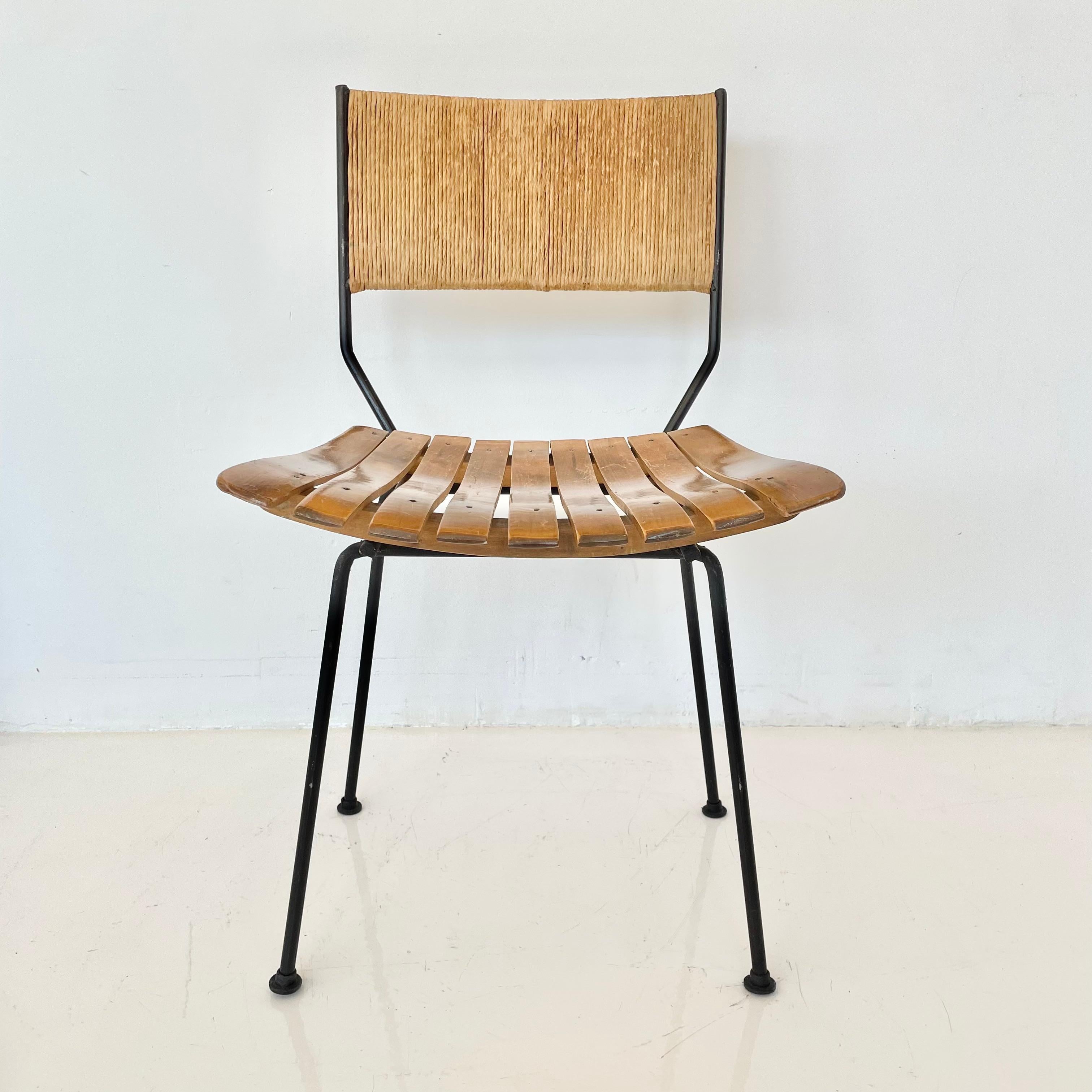 Chaise sculpturale Arthur Umanoff avec dossier en jonc, assise en bois à lattes et pieds en fer. Cadre en métal dans une finition adobe vintage. Un design rare. Siège flottant. Bon état vintage. Une seule chaise est encore disponible. 
      