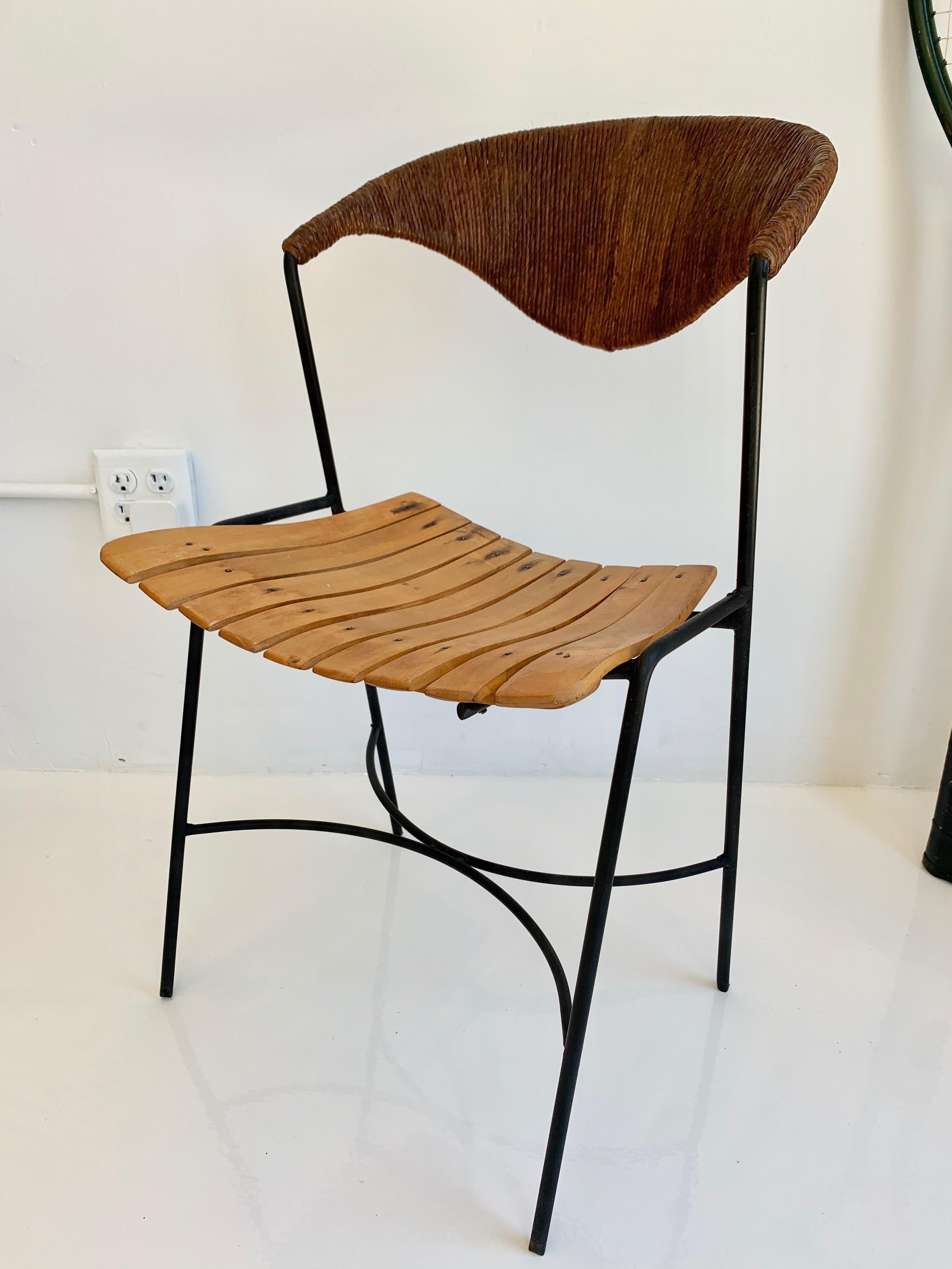 Sculptural Arthur Umanoff chairs with signature rush back, slatted wood seat, and iron legs. Floating backrest. Look great from all angles. Great vintage condition. Two available. Priced individually. 
 