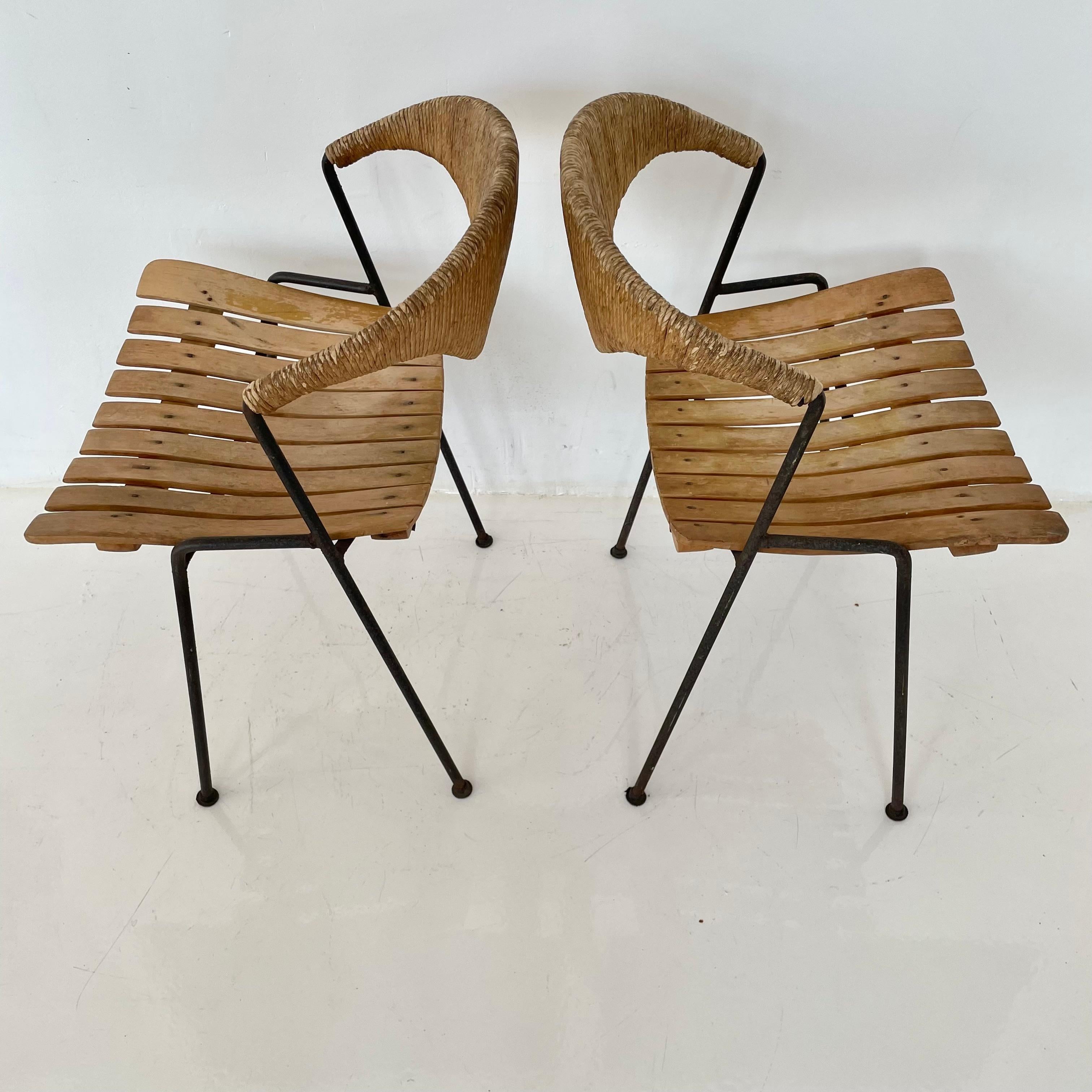 Early sculptural chairs by Arthur Umanoff. Chairs with signature rush back, slatted wood seat, and iron legs. Floating backrest. Look great from all angles. Good vintage condition. Two available. Priced individually.