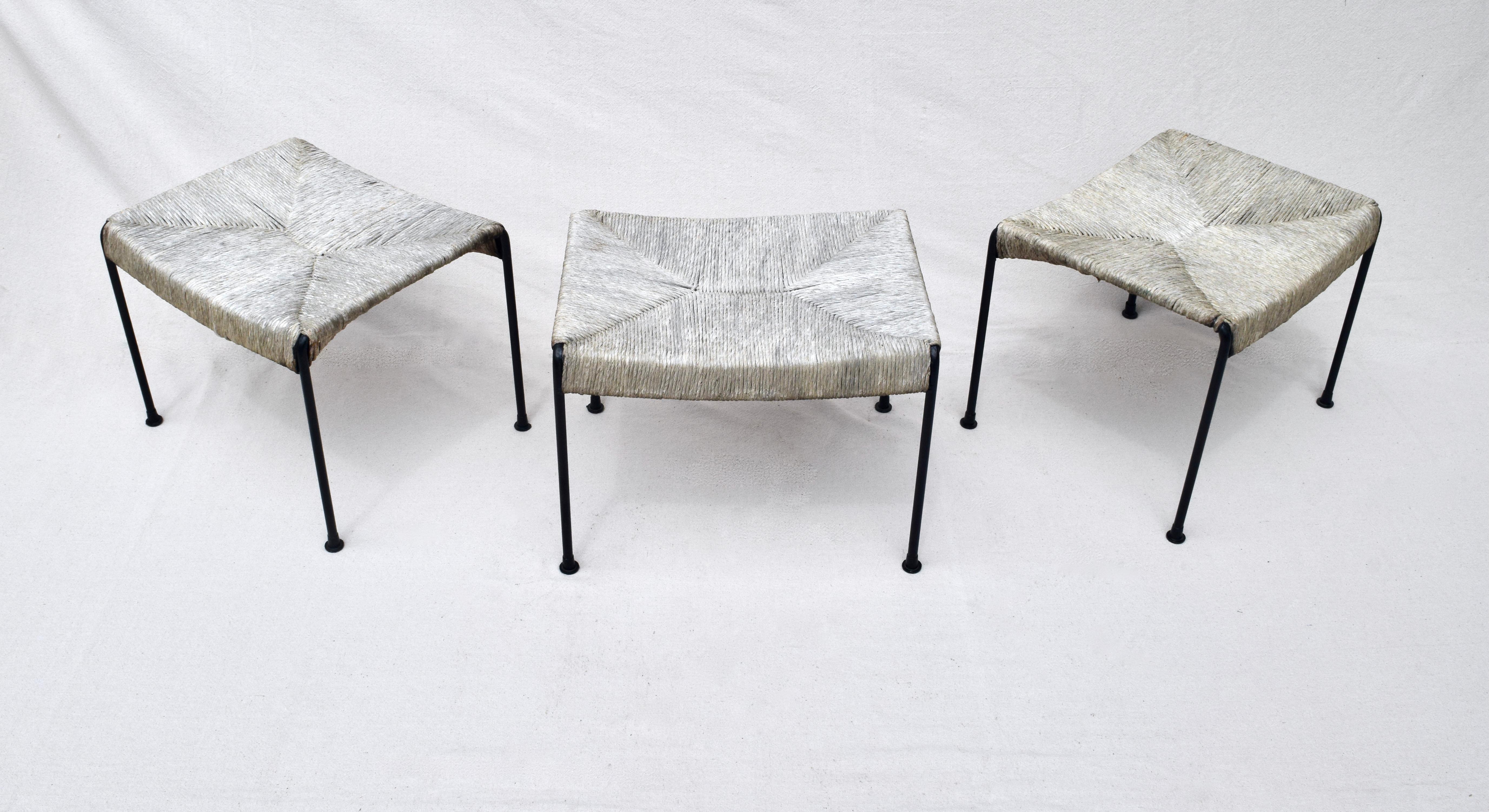 A trio of classic modern 1950's iron benches or stools designed by Arthur Umanoff for Raymor. Beautifully maintained with intensional Indoor full sun exposure has resulted in a marvelous warm homogenous silver gray finish to the woven rush, saddle