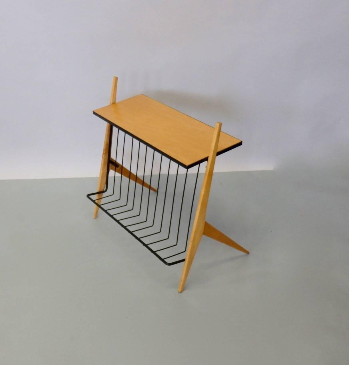 Arthur Umanoff designed Mid-Century Modernist magazine display side table. Wrought iron frame in black finish supports organic form blonde wood legs and blonde wood table top .