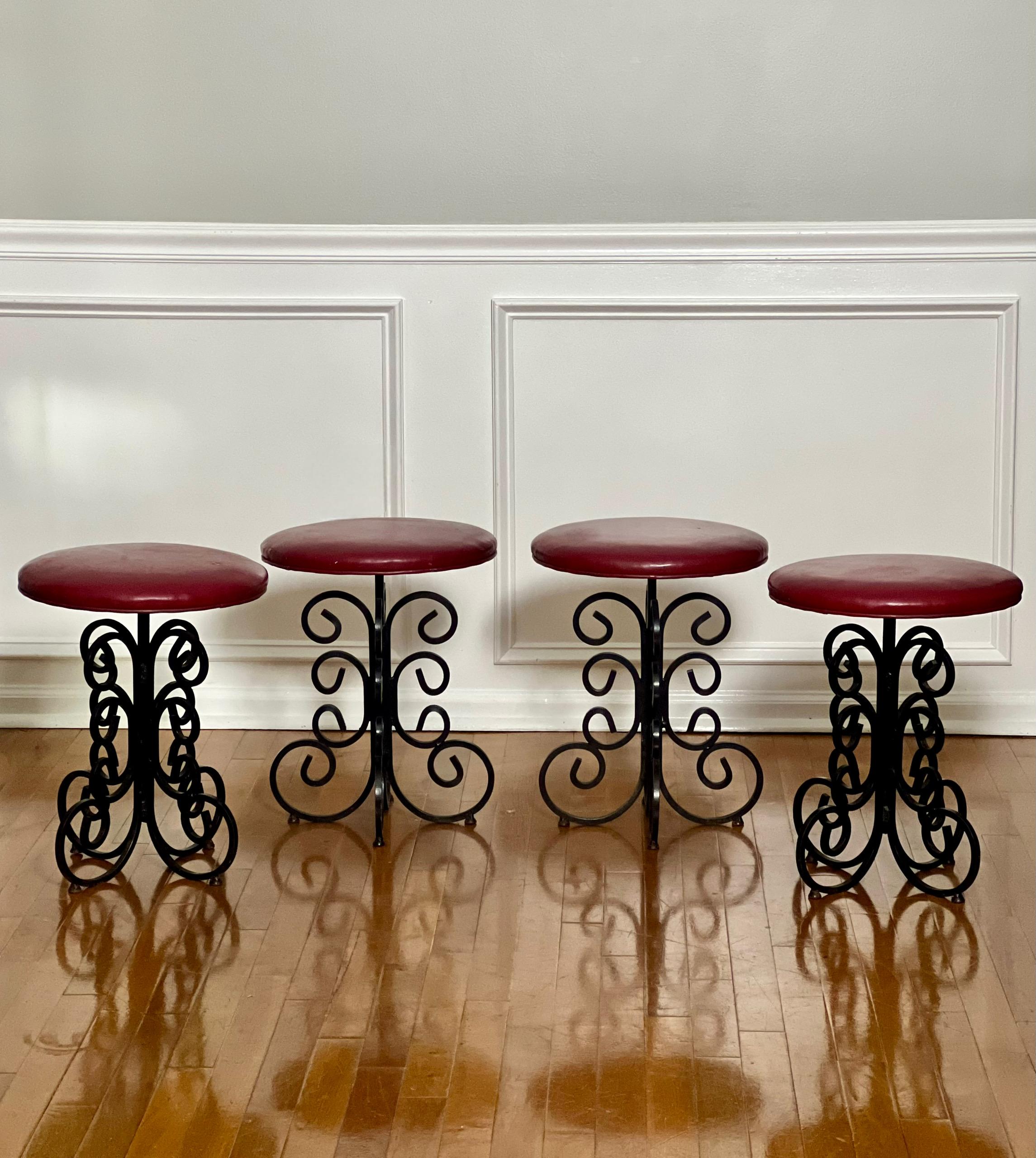Superbe ensemble de 4 tabourets en fer forgé Arthur Umanoff vintage midcentury en faux cuir rouge. Tabourets uniques et originaux avec de lourdes volutes. Excellent choix pour entourer une table de bistrot sans prendre la place d'une chaise. Facile