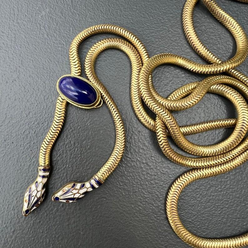 Una straordinaria collana/cintura con catena a serpente flessibile dell'epoca Art Deco con una testa smaltata in blu e bianco che penzola graziosamente all'estremità. Questo pezzo versatile può essere indossato sia come collana che come cintura,