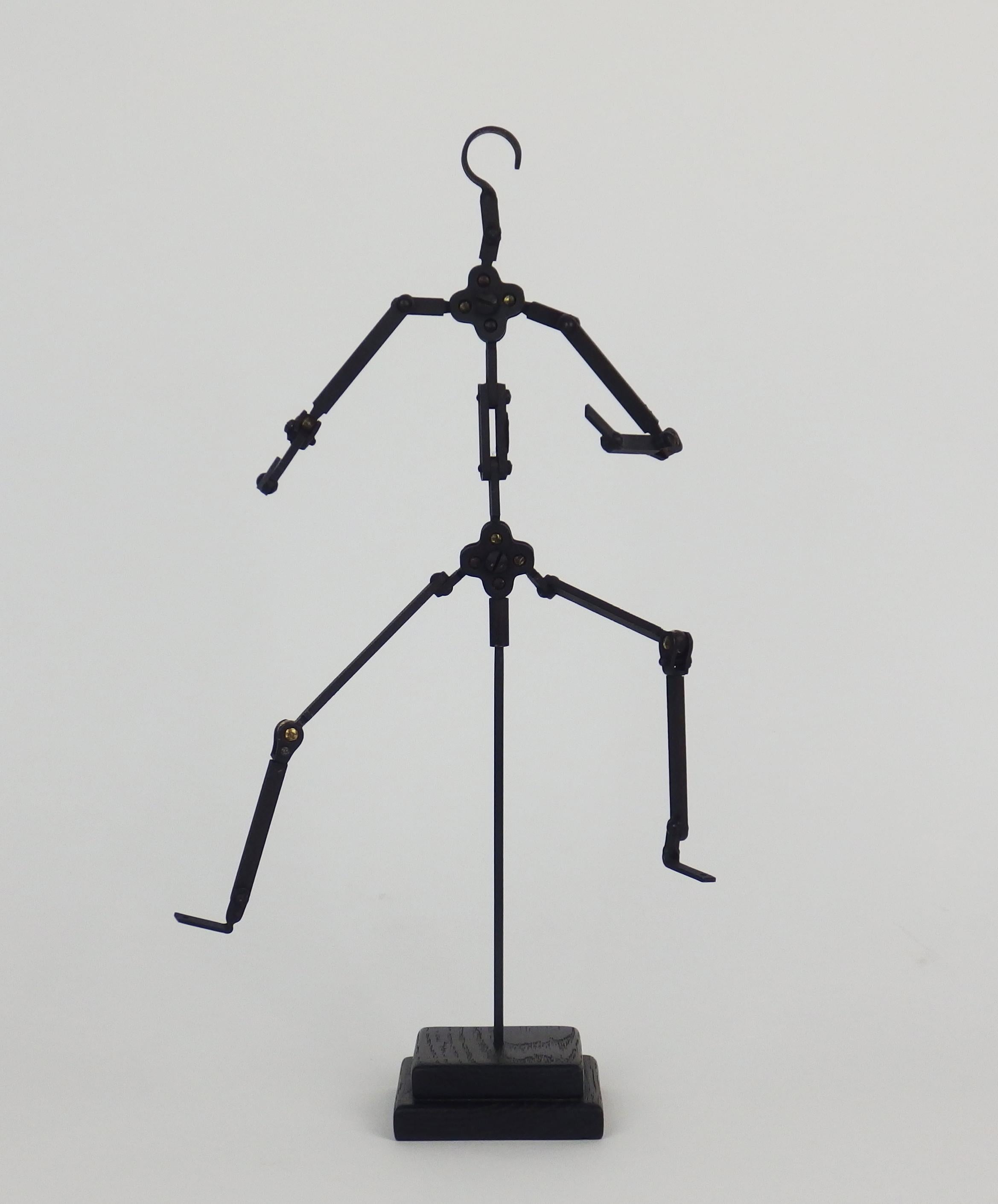 An articulated artist mannequin in iron with brass articulations on an oak base. Label 