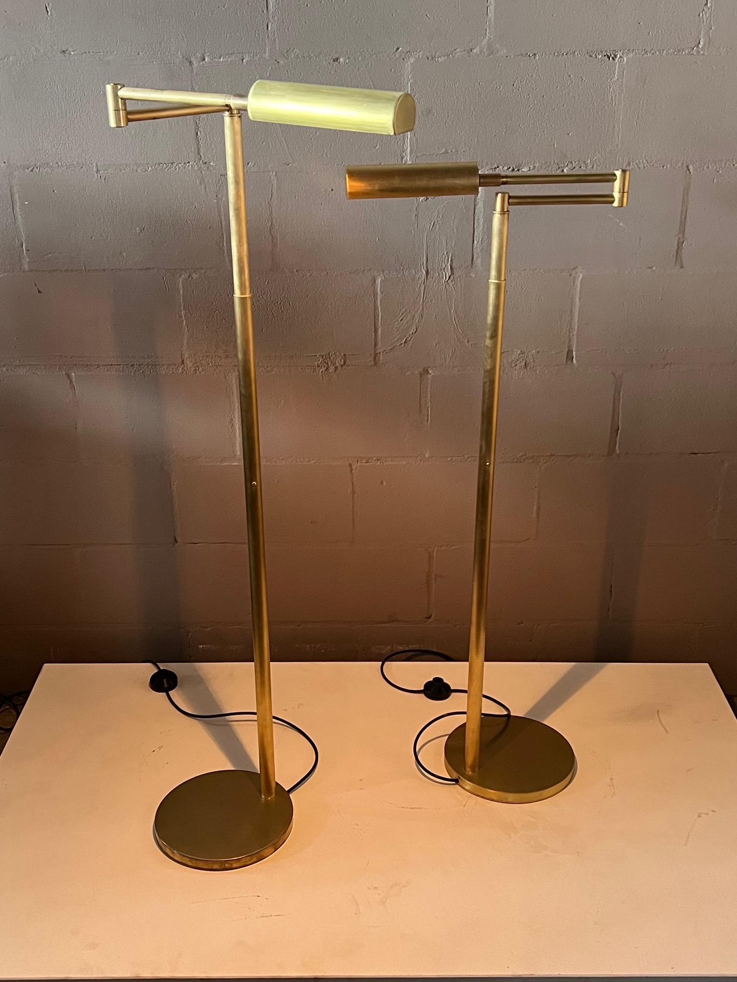 A pair of brass reading lamps by Koch & Lowy, stamped OMI. Articulated shades create many possibilities. Satin brushed finish with some patina and discoloration. Original porcelain sockets, rewired with foot switches.