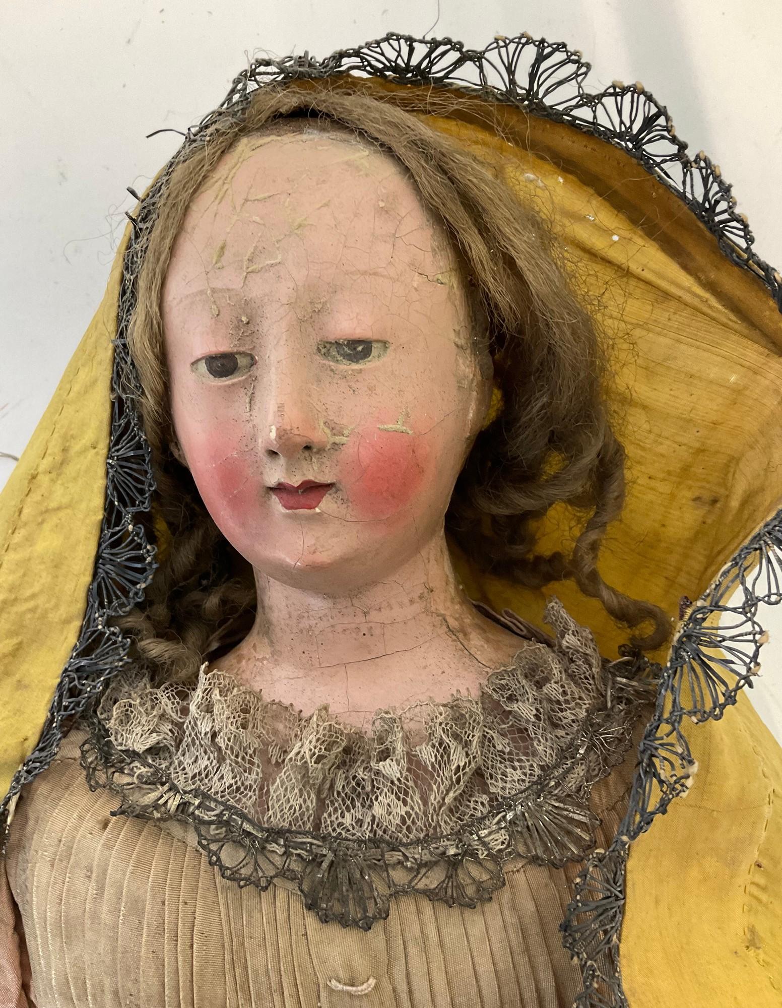 Very beautiful doll with papier-mâché head and wooden body, articulated.

She wears a superb dress embroidered with lace.

Her very elegant outfit is enhanced with a veil which hides curly hair

18th century doll, with gaps and wear (see