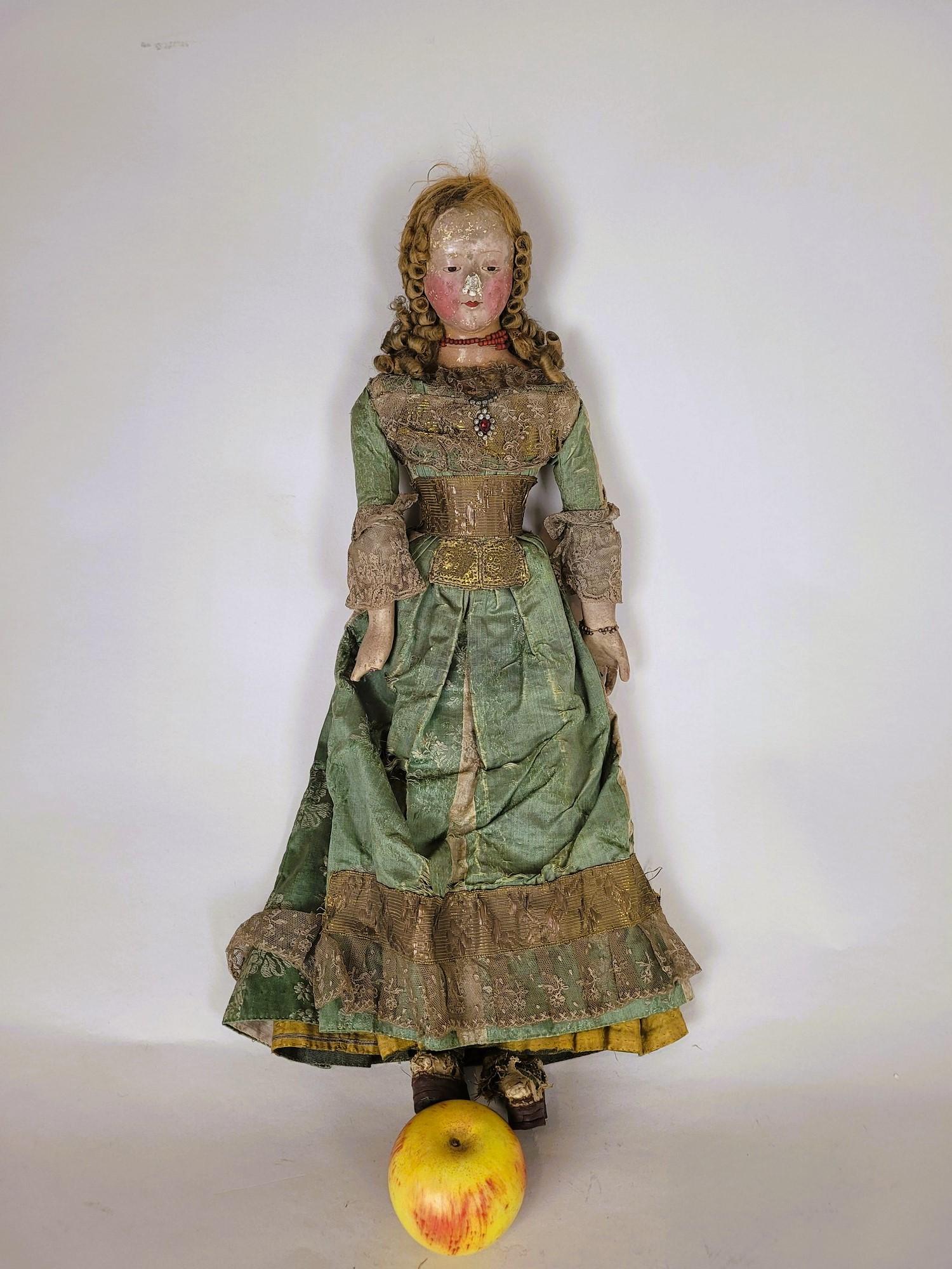 Very beautiful doll with a papier-mâché head and a wooden body, articulated.

She wears a superb green dress, embroidered with silver/gold thread and lace.

Her very elegant outfit is enhanced with jewelry (coral necklace) and an elaborate