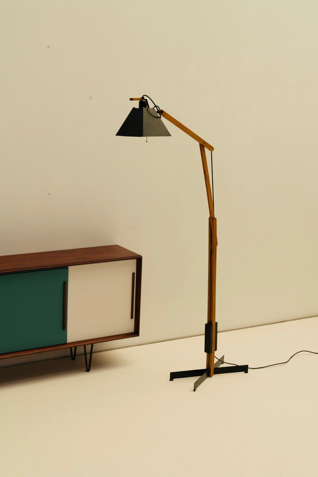 The lamp's minimalist structure features a sleek, angular wooden frame that showcases the natural beauty of the wood grain, embodying the clean lines and functional elegance typical of the mid-century aesthetic.

The adjustable arm allows you to