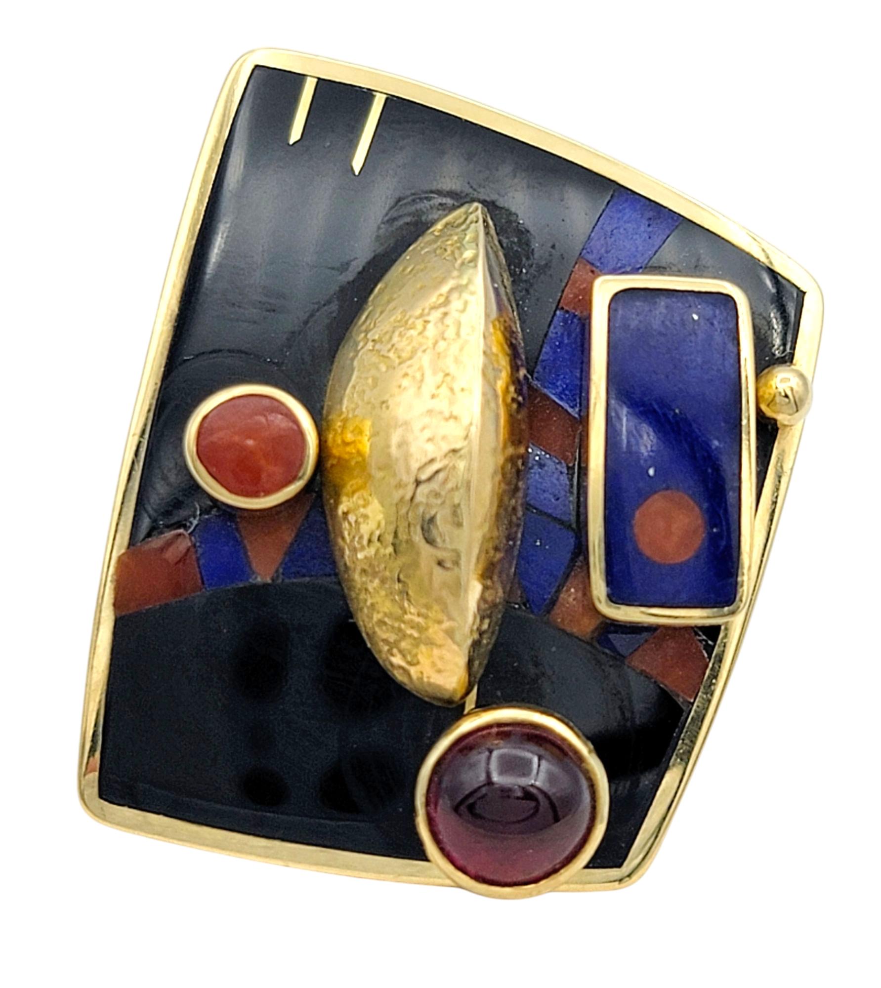 Cette bague extraordinaire est une célébration du mouvement, de la couleur et de l'expertise artisanale. Avec une incrustation artistique de corail, de grenat, d'onyx noir et de lapis-lazuli, le design est rehaussé par des pierres précieuses