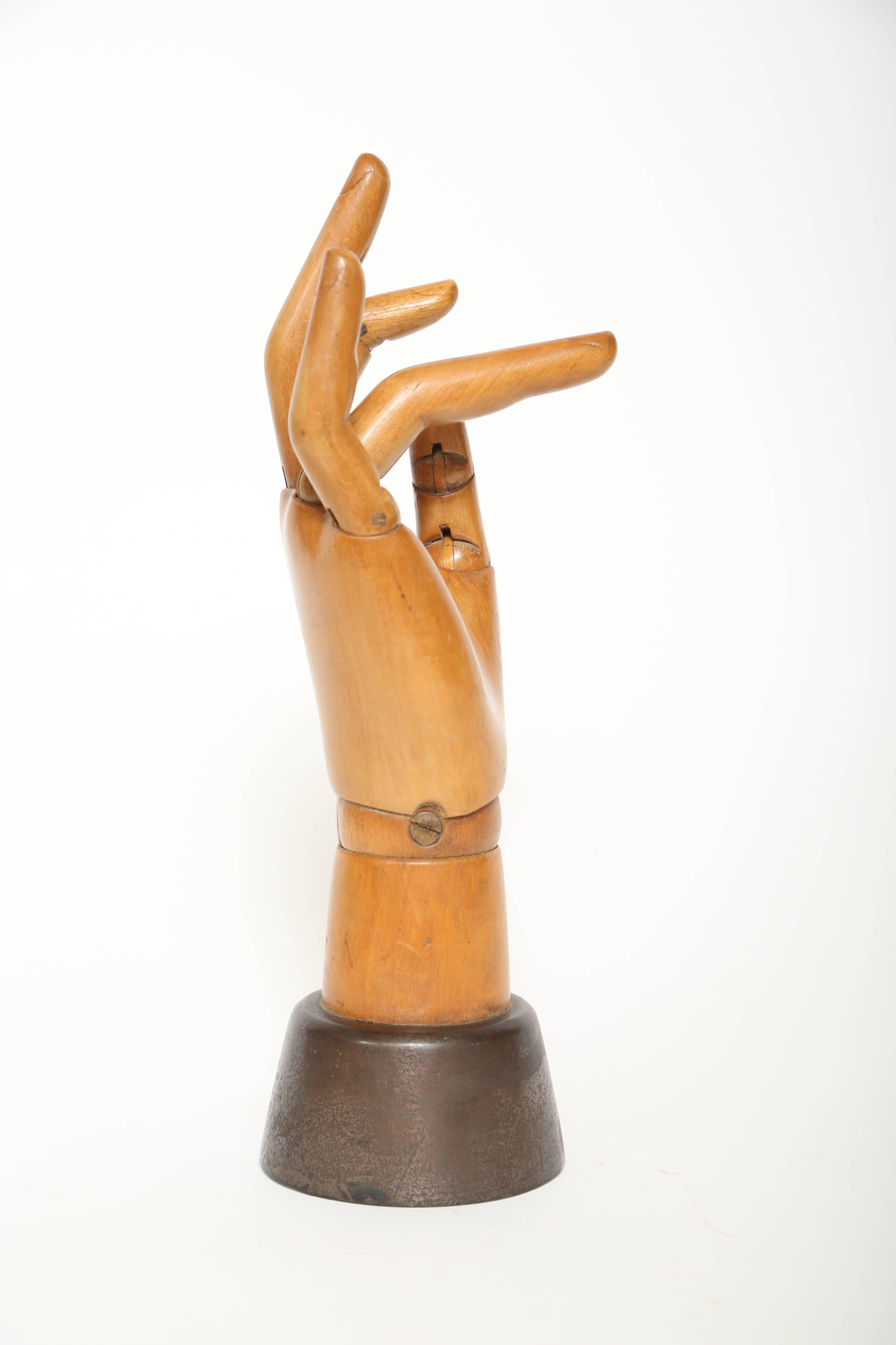 Life size articulated wooden hand mannequin with a weighted iron base. Used by artists and sometimes by shops to display gloves, jewelry and so on.  This piece is great quality with nicely carved fingers and finger nails displaying good honey color