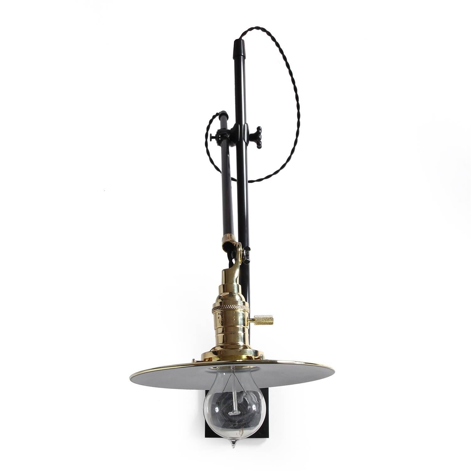 A beautifully fabricated and graceful wall lamp in patinated steel and polished brass having an articulating arm emanating from a stepped rectangular wall plate. Manufactured by O.C. White in the early 1900s.
