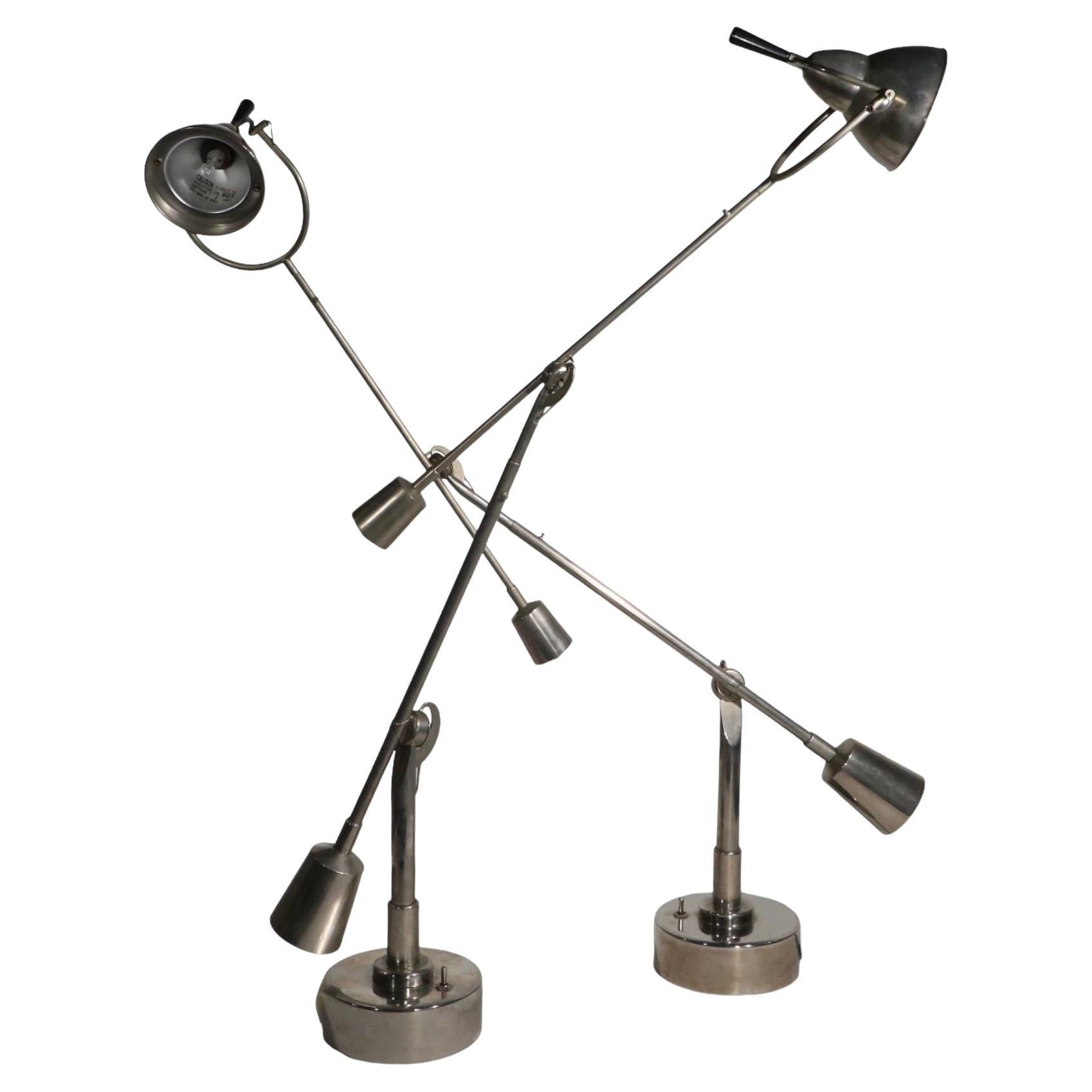 Pair of iconic articulating desk, table lamps, originally designed in the 1920's by Edouard Wilfred Buquet, this example is circa 1990's. The lamps feature two arms, which are fully jointed, and the hood shade swivels and tilts to position the