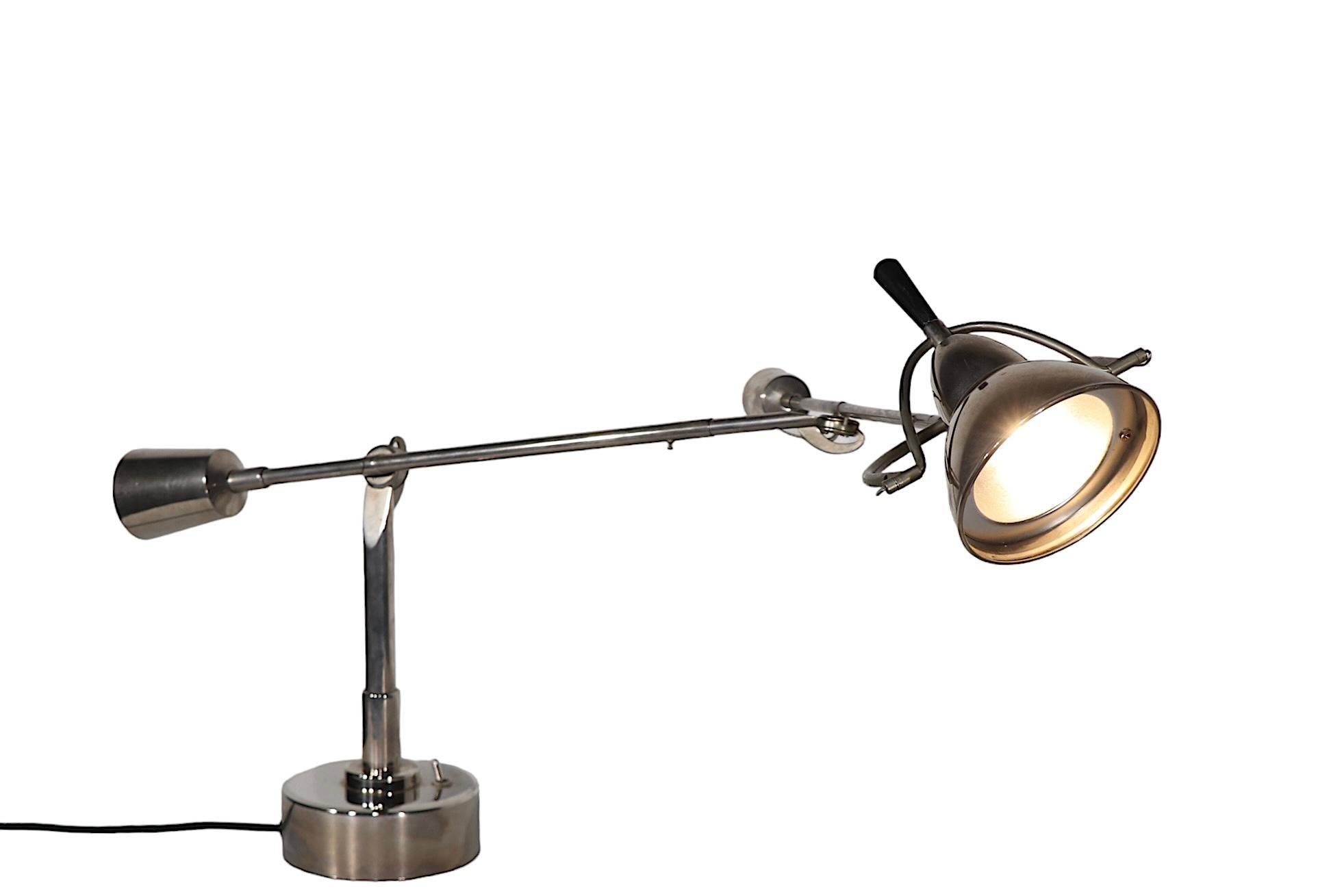 Iconic articulating desk, table lamps, originally designed in the 1920's by Edouard Wilfred Buquet, this example is circa 1990's. The lamp features two arms, which are fully jointed, and the hood shade swivels and tilts to position the light. Well