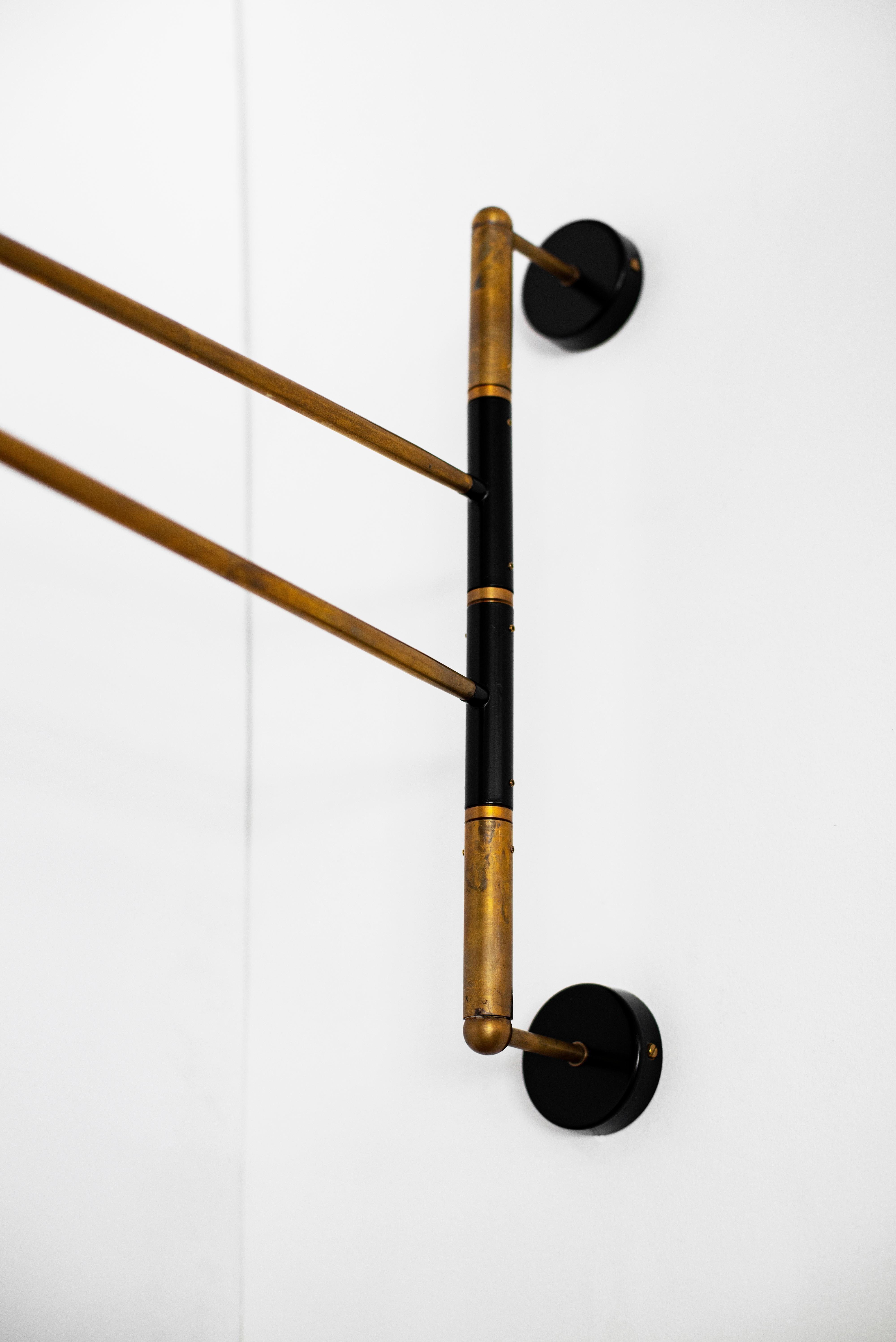 Great Italian articulating wall sconce with two swinging brass arms, each different lengths with unique black metal shades. Newly produced in Italy, wired to American standards.