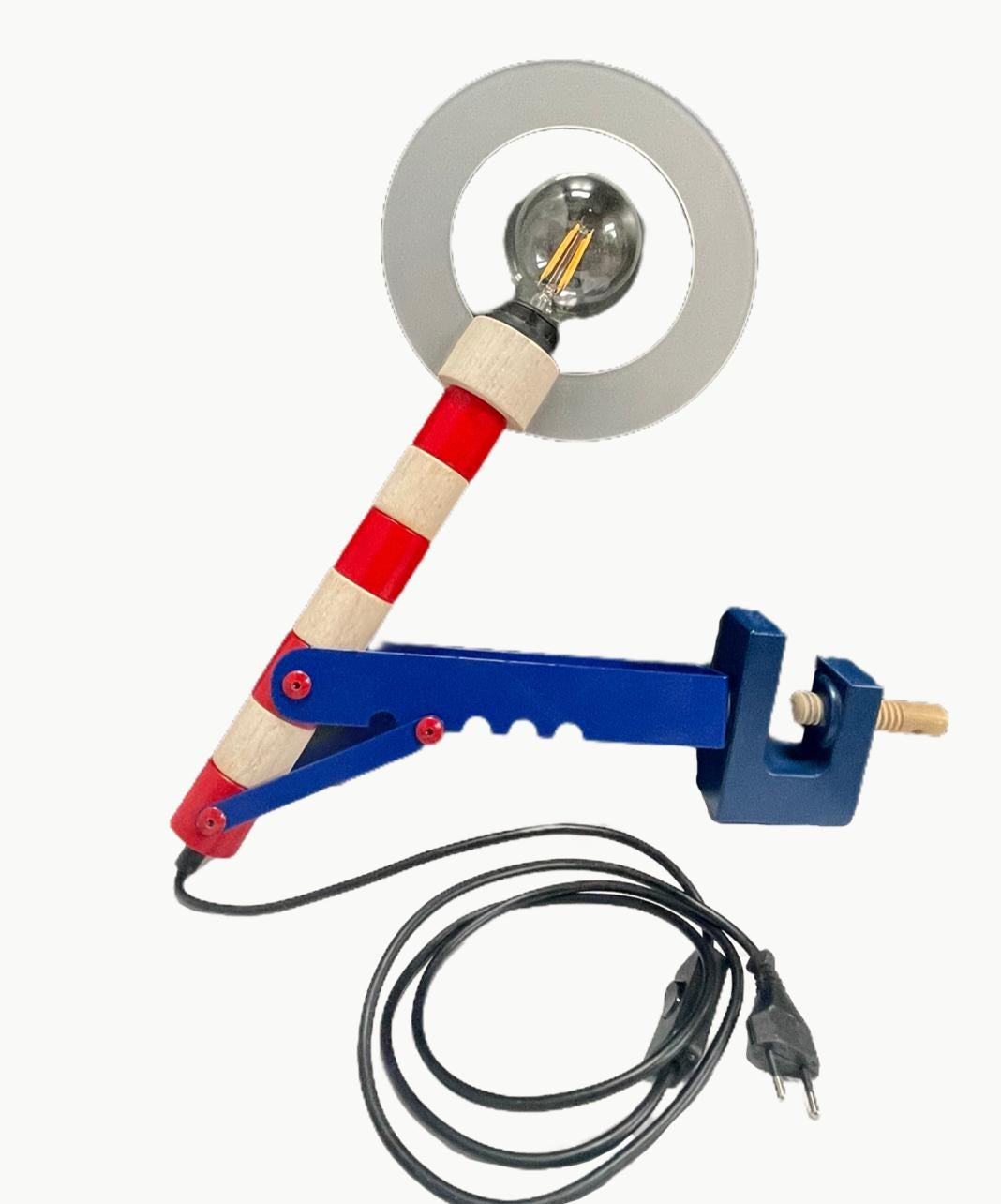 Wonderful drafting lamp in primary colors, reminiscent of 1980s Memphis Milano design, made of wood and metal. Striped arm in red and white with wooden rotating components. Wood dowel tightens the base so that it can clamp on to a