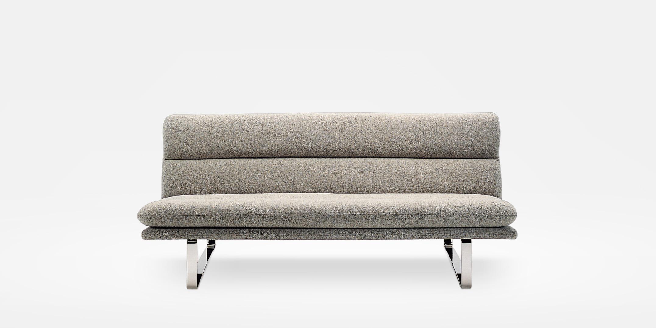 A sofa by Kho Liang Ie. Restrained simplicity. Frame of pressed beech upholstered with moulded foam on a metal base. With integrated seat and back cushion.

Base: Two metal straps: clear flat. Finish: chrome or powder coat. Seat and back: