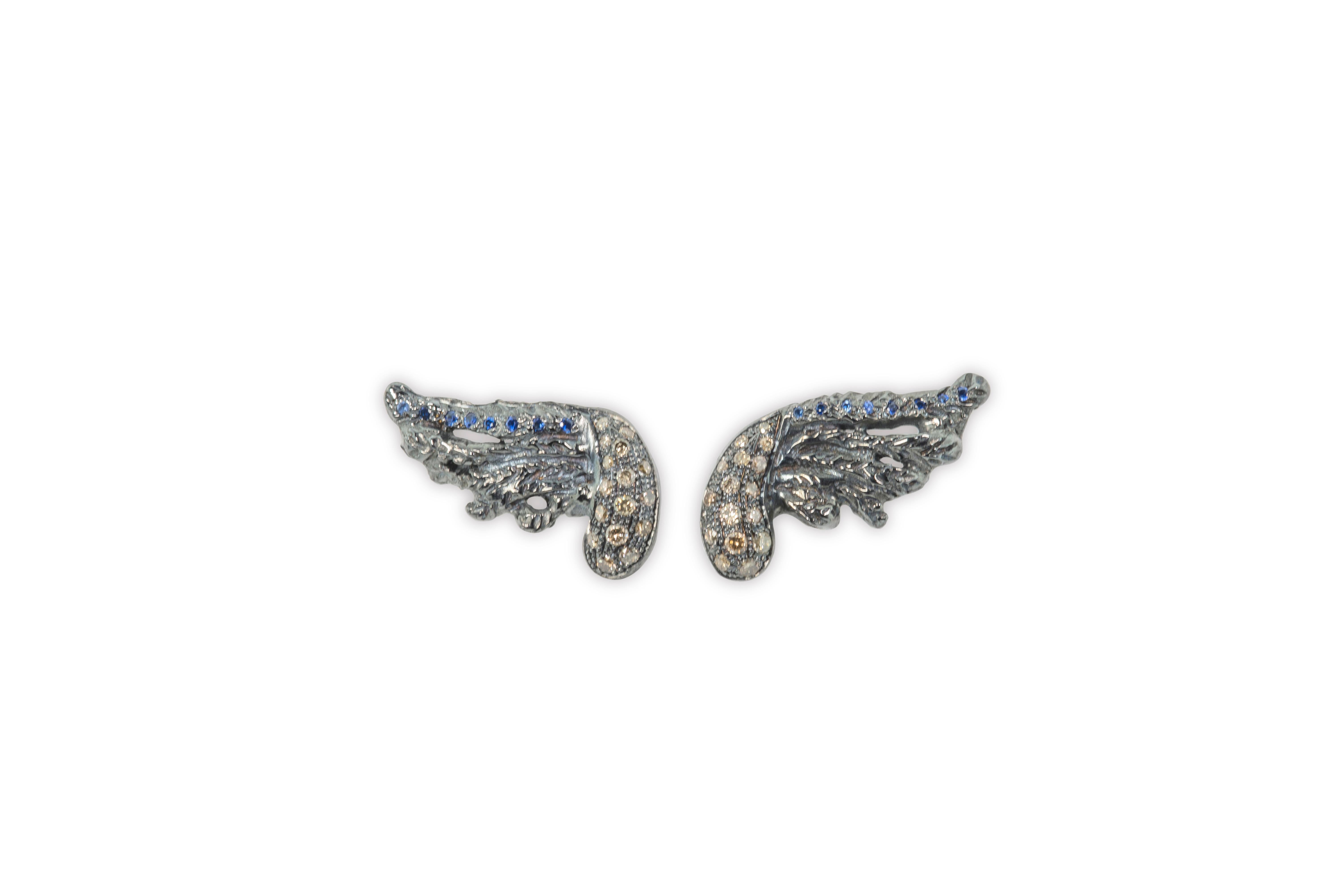 Artisan 18 kt White Gold 0.30 Karat Brown Diamonds Feather Blue Sapphires  Stud Earrings
Here there is a a beautiful pair of stud earrings handcrafted in 18 karats white gold and embellished with 0.30 karats brown diamonds and blue sapphires.
This