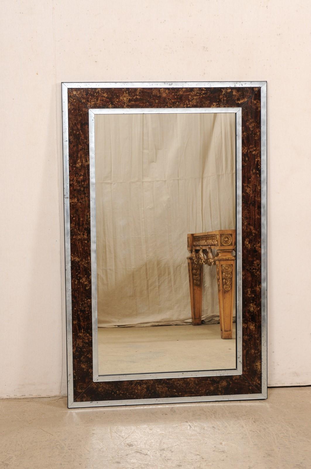 Magnifique miroir mural rectangulaire de fabrication artisanale, en verre églomisé et antiquité. Ce miroir rectangulaire de belle taille a été fabriqué artisanalement avec un entourage en faux églomisé de tortue, de couleur brune, encadré par des