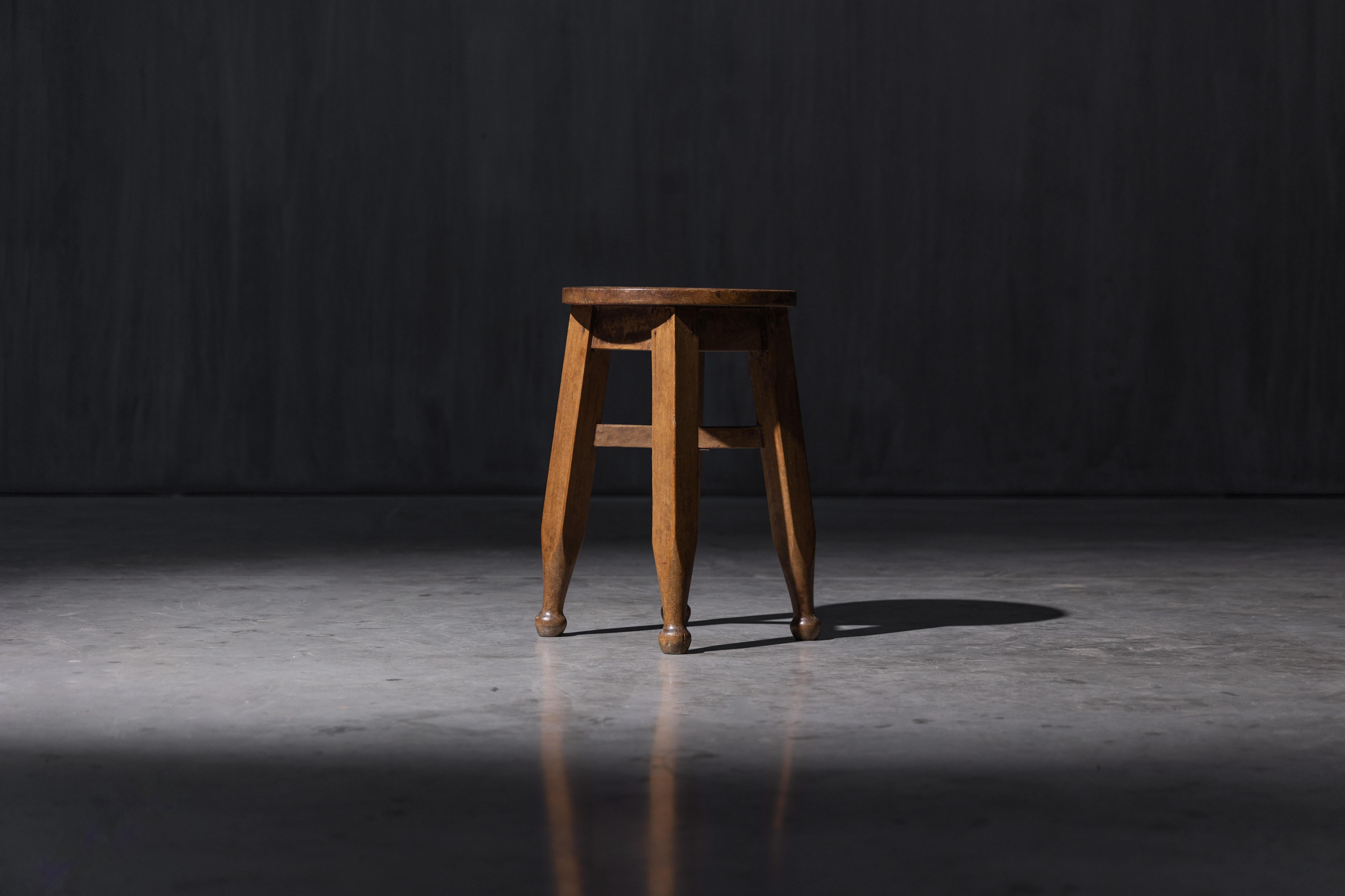 Un taburete de madera de principios del siglo XX fabricado según la tradición inglesa de las Artes y Oficios, con un diseño sencillo y resuelto y auténtica artesanía. Su asiento redondo y sus robustas patas presentan una sutil ebanistería y una