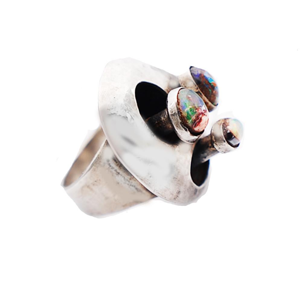 Smiling Face features an artisan's custom design with Opals set in a Ring made of 925 Sterling Silver.
 A Protruding face pops out of a hammered disk shaped ring which is nearly 1 inch in diameter. Each stone is bezel set on varying lengths from the