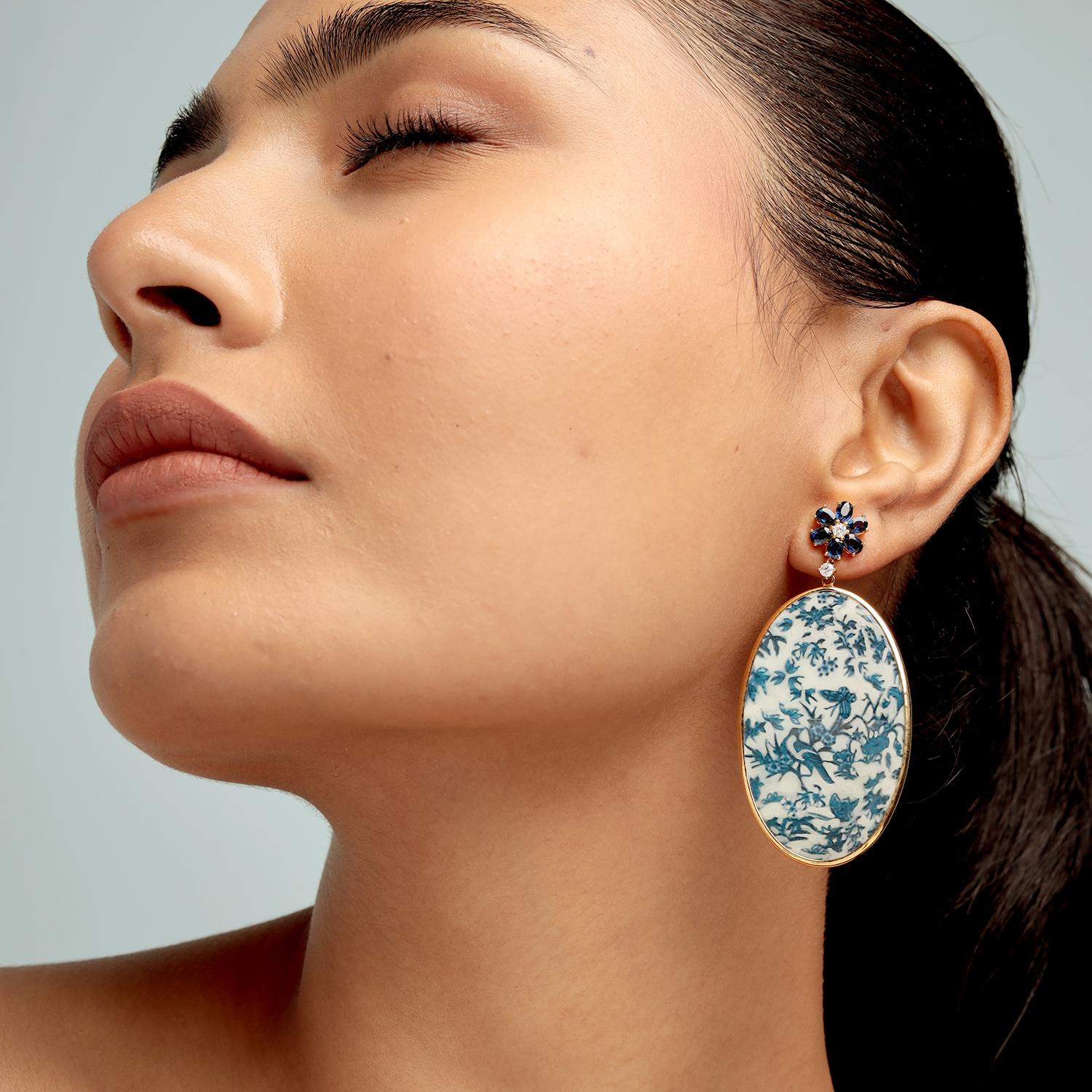 Questi eccezionali orecchini a goccia di Artisan presentano 32,60ct di bachelite dipinta a mano, ornata da un motivo botanico bianco e blu, coronata da sommità di fiori di zaffiro (2,58ct) e accenti di diamante (0,25ct), il tutto incastonato in