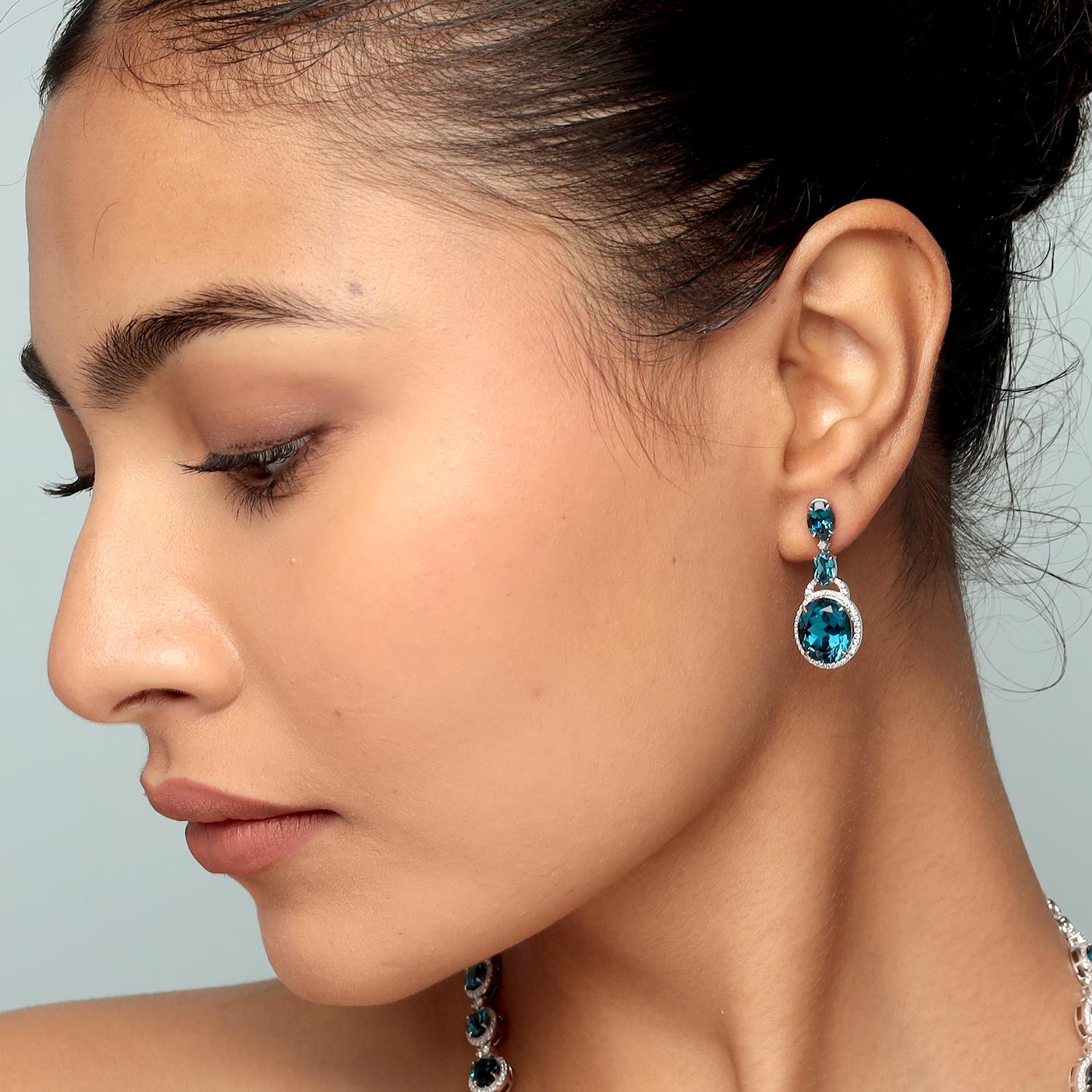 Questi splendidi orecchini a goccia di Artisan presentano un totale di 15,87ct di topazio blu vivido in ovali graduati incorniciati da 0,35ct di diamanti scintillanti, il tutto incastonato in 5,306g di oro bianco 14K. L'elegante Silhouette di 30x12