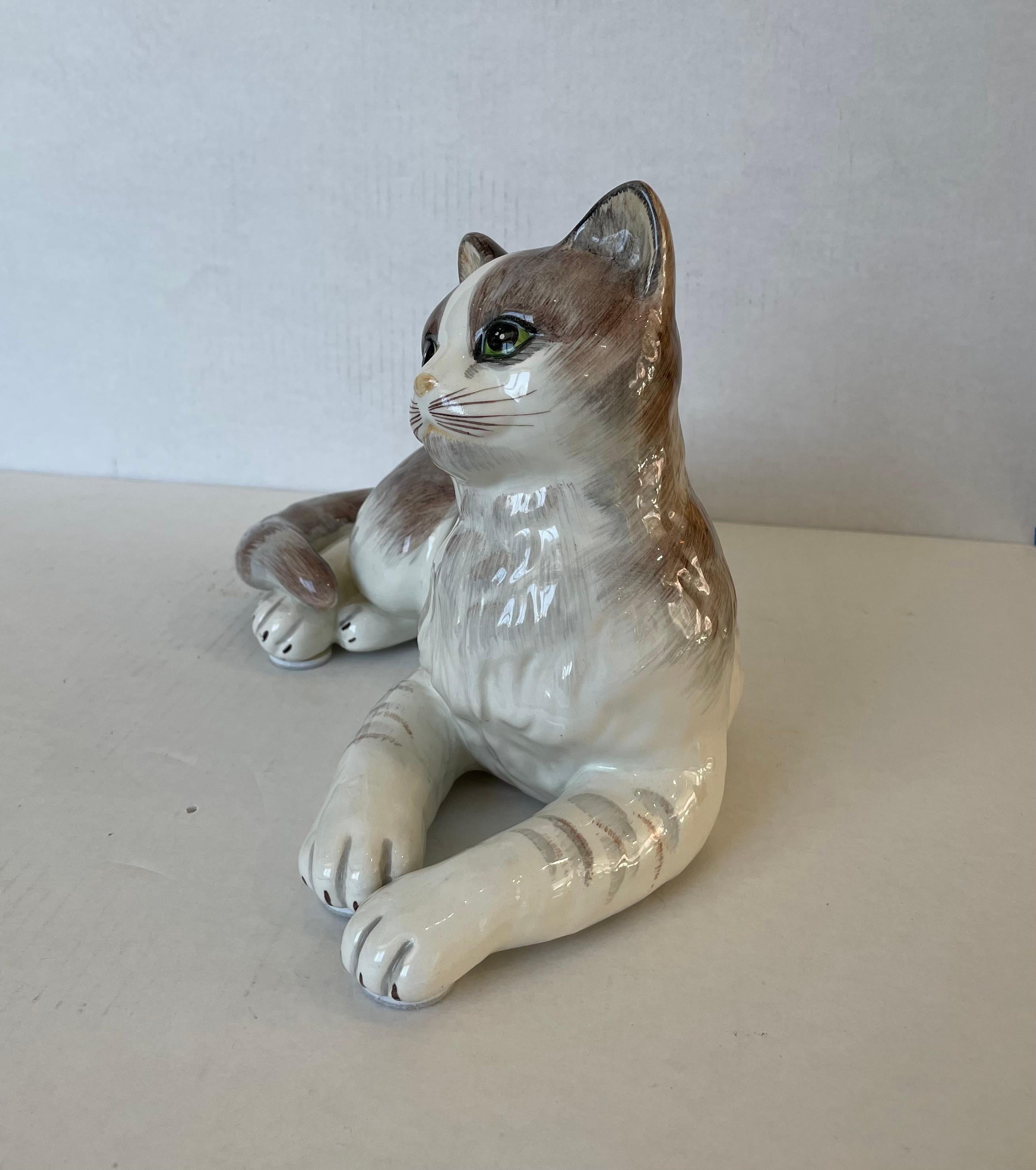 Diese stilvolle und schicke italienische Kunsthandwerksfigur einer ruhenden Katze setzt mit ihrer Form und der Verwendung von MATERIALEN ein subtiles Statement.  Das Stück ist handbemalt in schönen cremeweißen, grauen, braunen und grünen Farbtönen. 