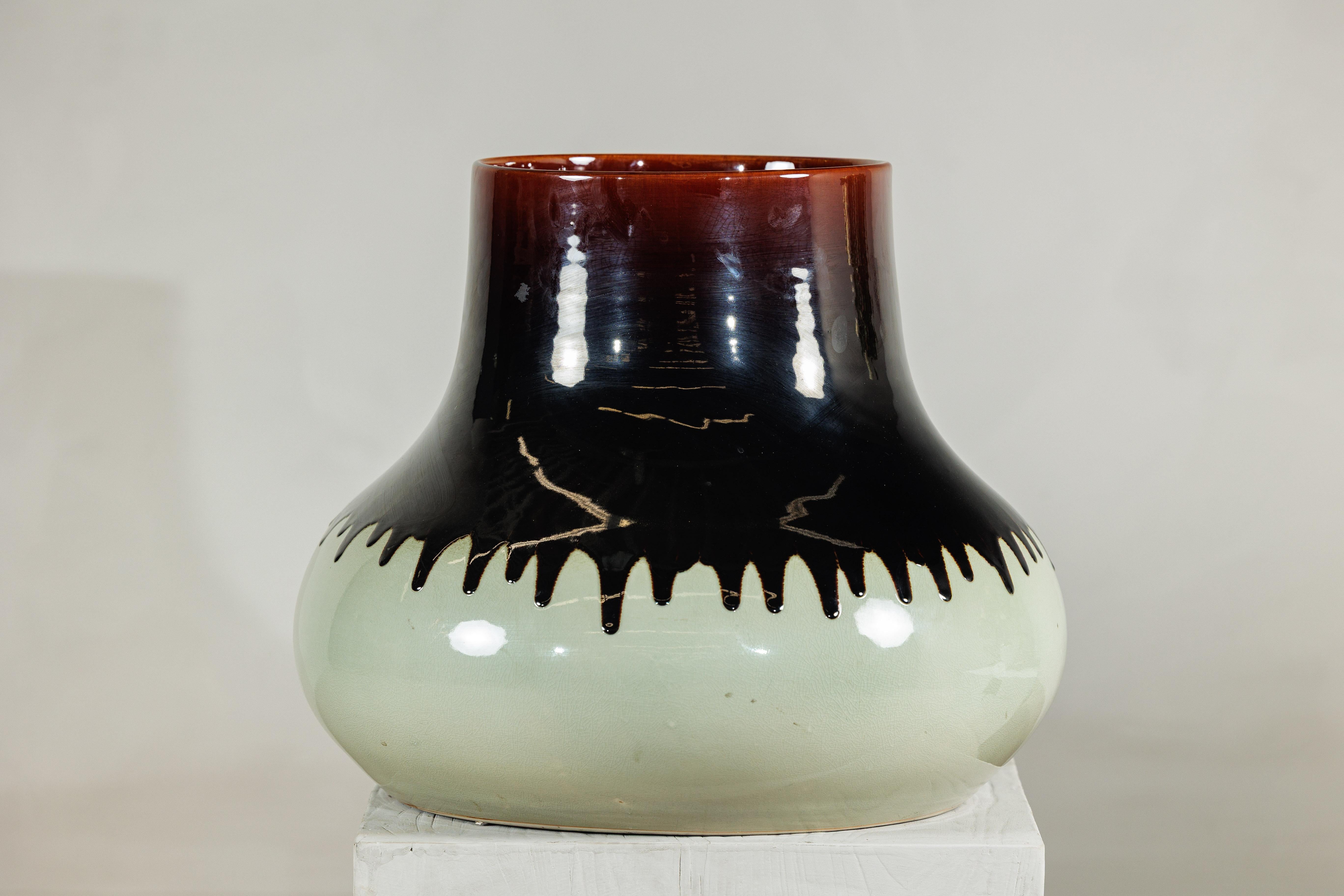 Un vaso artigianale in ceramica che si distingue per la sua forma audace e per la sorprendente smaltatura bicolore. Il pezzo è caratterizzato da un corpo ampio che si assottiglia elegantemente fino a una vita stretta, per poi salire fino a un collo