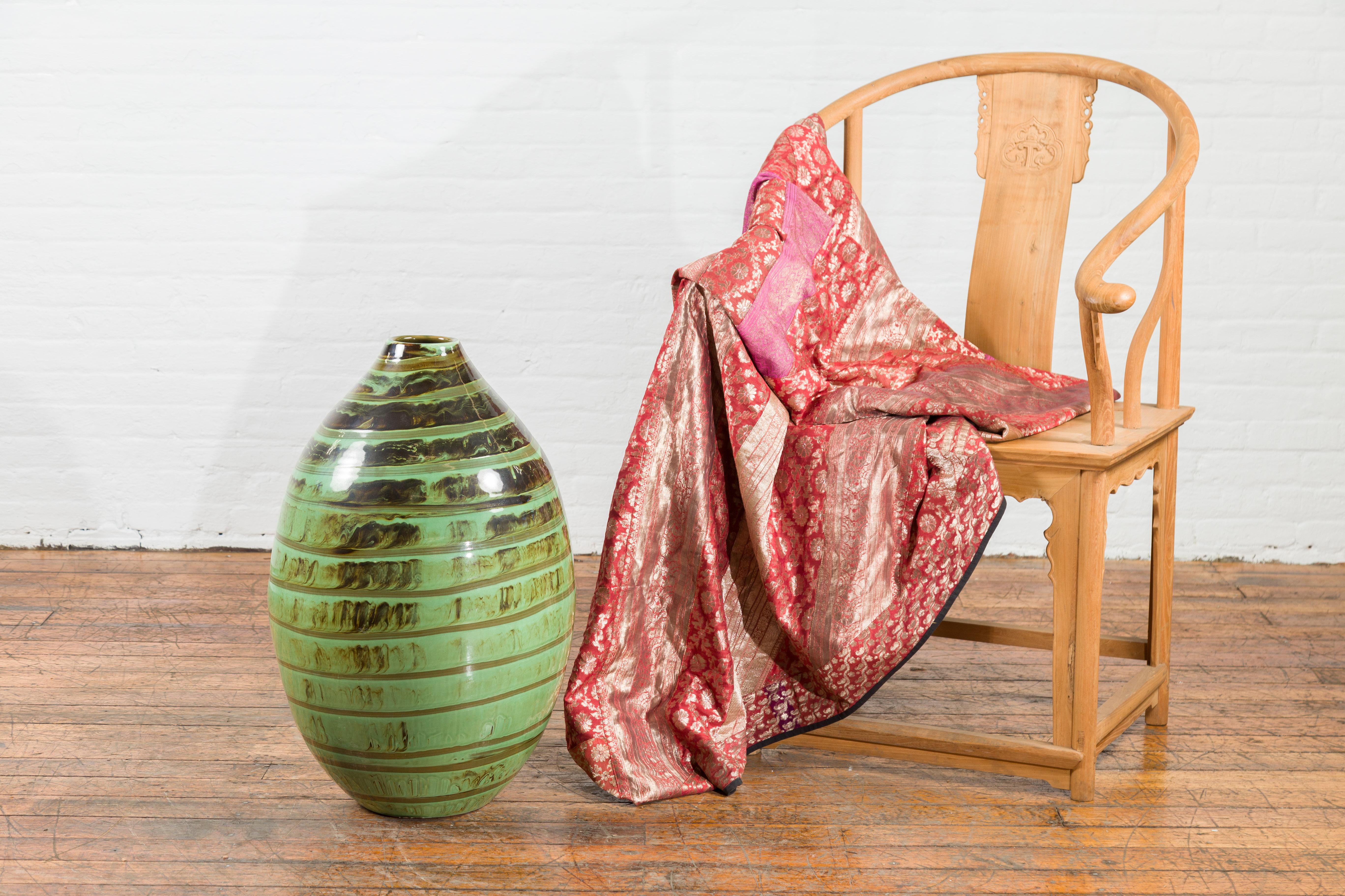 This generously scaled ceramic vase charms with its bold silhouette and dynamic glaze. Shaped with a rounded body that narrows to a petite mouth opening just under 4 inches in diameter, the form evokes classic amphora shapes with a modern,
