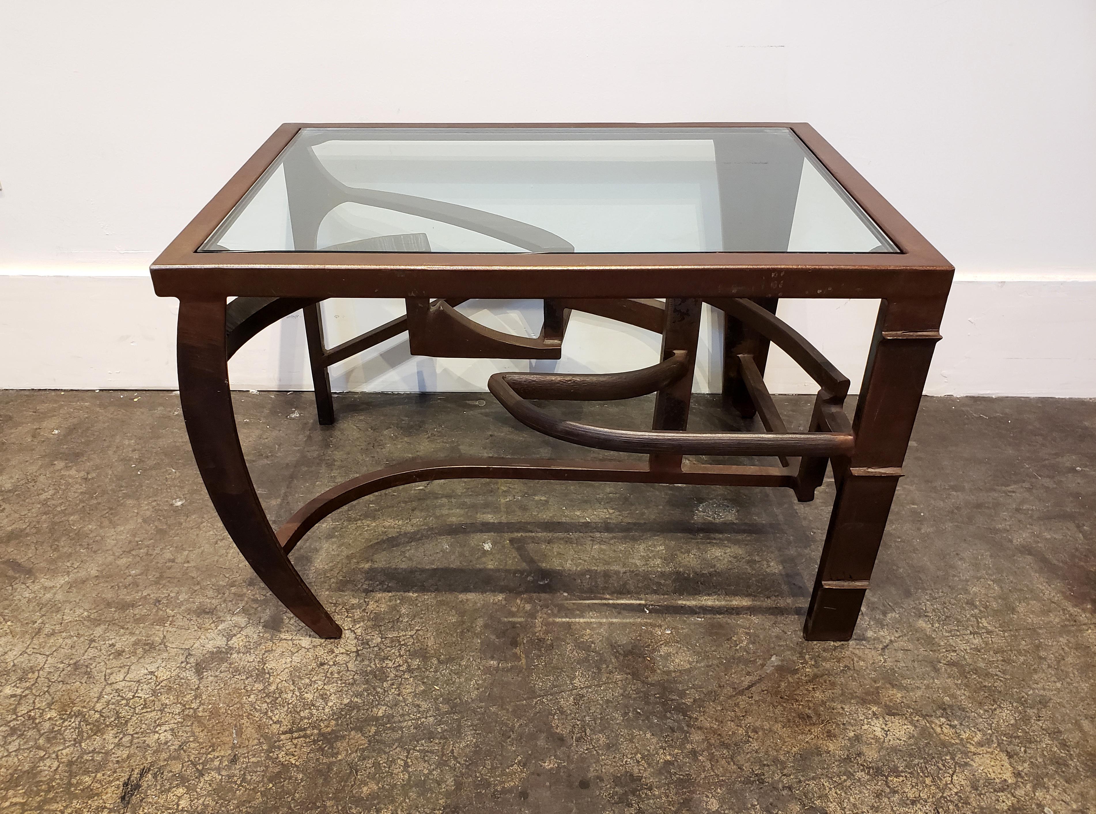 Iron side table with dynamic, intertwined sculptural base. Iron has warm patina. Top is finished in glass. Rich in detail and movement. As much a work of sculptured art as a functional table.