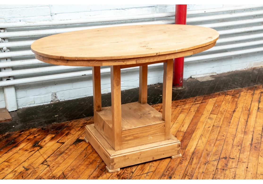 A very well made Rustic Style Table suitable as a Center or Breakfast table. An unusual pine table with oval top mounted on a square double tiered base. Raised on square legs attached to the top tier. With flat feet. 
48 x 29 1/4