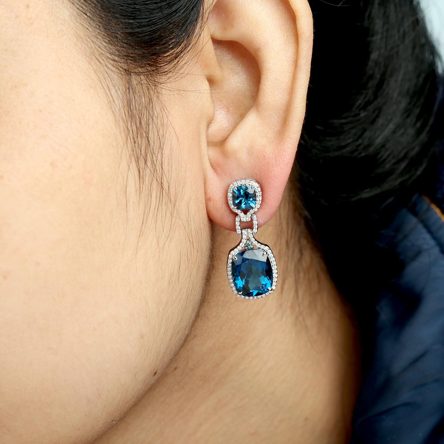 Ces boucles d'oreilles glamour d'Artisan présentent une topaze bleue taille coussin de 16,04 carats, encadrée par 0,61 carat de diamants étincelants et sertie dans 7,441 g d'or blanc luxueux 14K. Le design audacieux de 31 x 13 mm est rehaussé de
