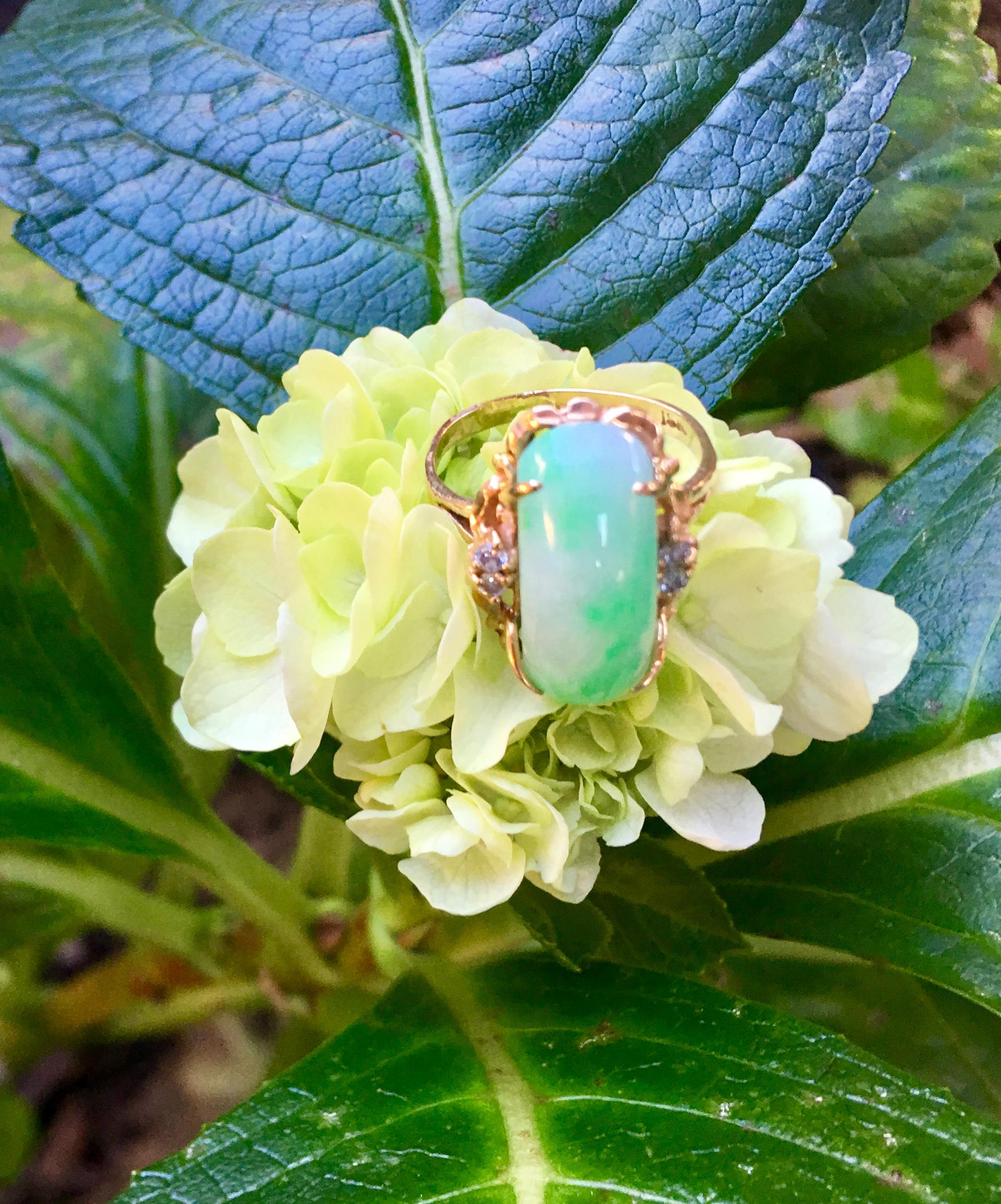 Beautifully proportioned, 18 karat yellow gold estate ring from the 1970s features a large, custom curved cut, elongated natural apple green and white variegated jade stone, prong set in 18 karat yellow gold and accented with 4 prong set, round