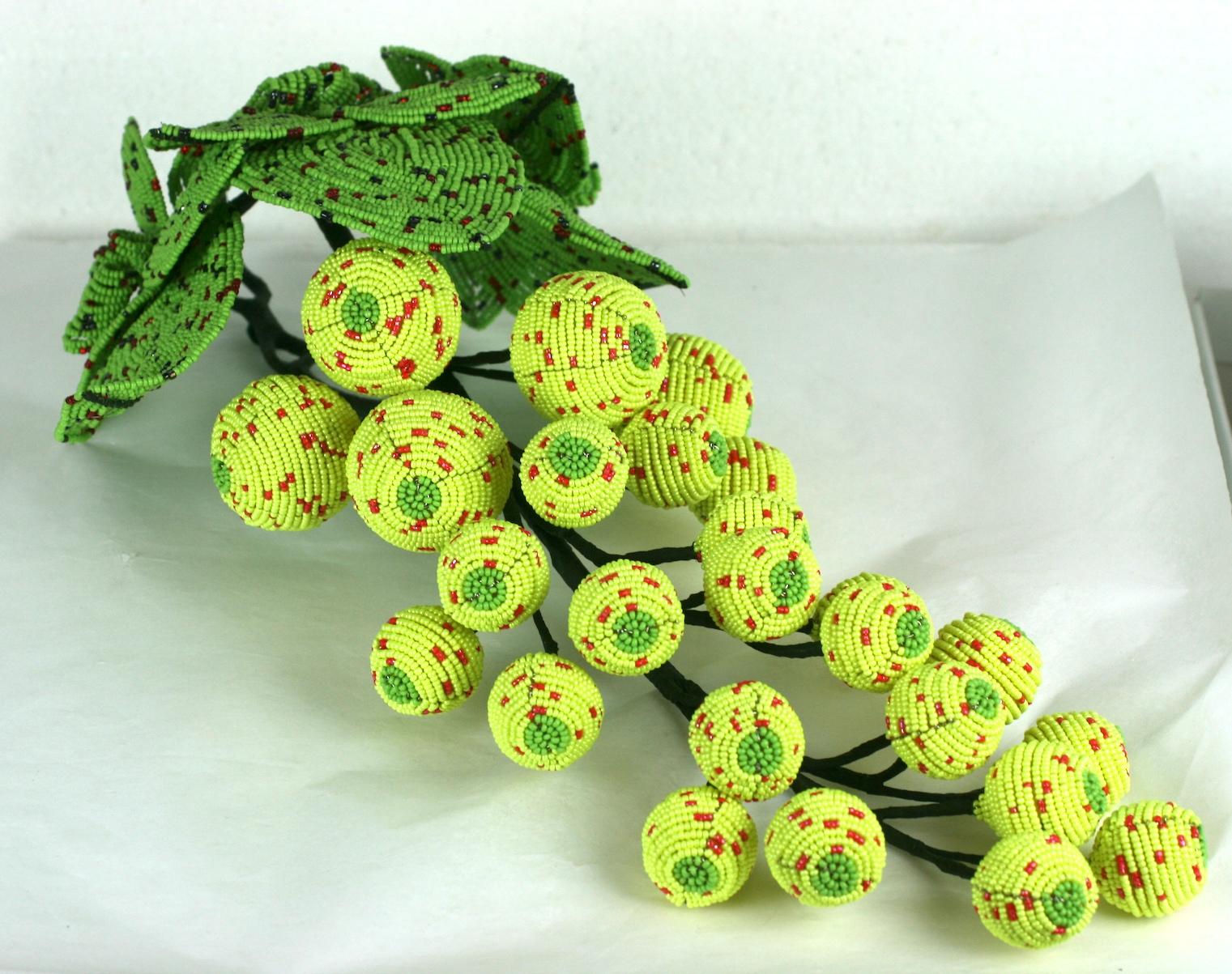 Hand beaded grape ornament made of vintage and contemporary glass beads in vibrant colorations. Neon yellow grapes beaded on foam and cork bases with rasberry speckles under a series of hand beaded grapes leaves in matte lime speckled with hematite