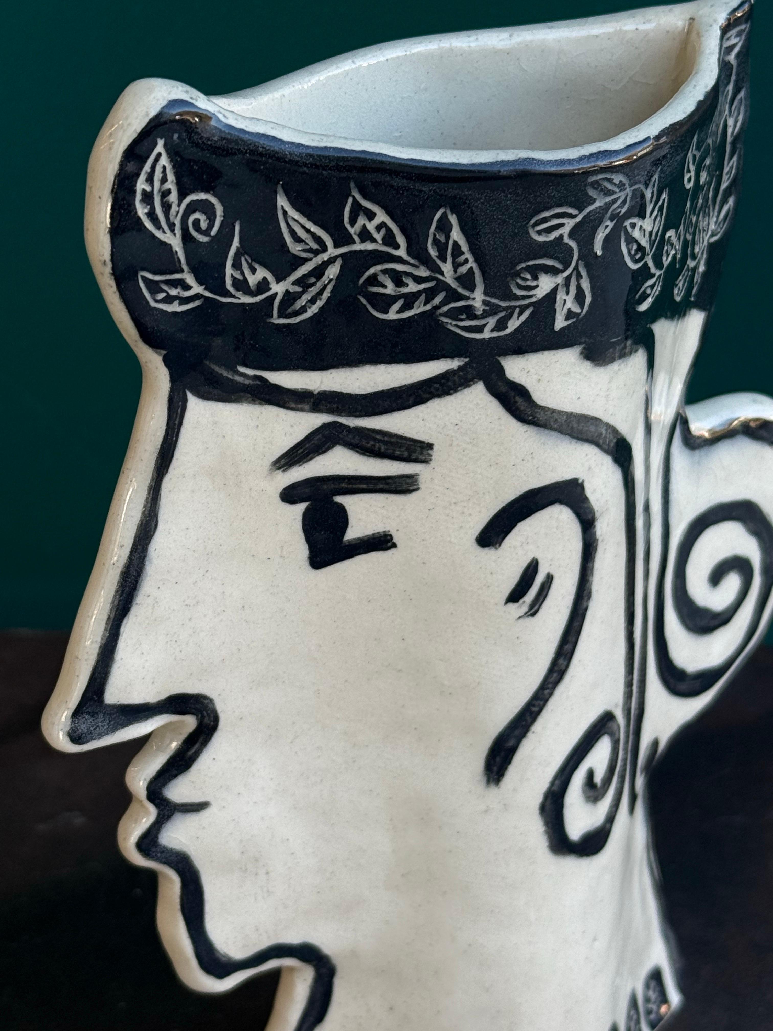 Vaso medio dal volto femminile con contorno nero dell'artista Susanne Portanova

Un mix di vecchio mondo e tecnica new age. Design altamente scolpito realizzato in gres, dipinto sottosmalto su argilla dura e pelle e smalto trasparente, cotto in