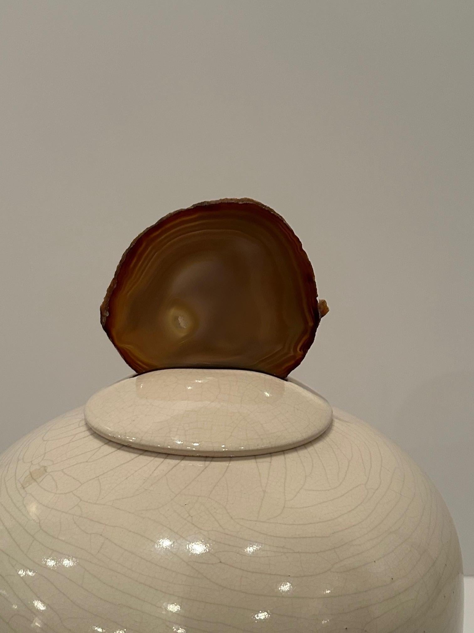 Dramatique urne moderne à couvercle en céramique de couleur crème, de forme large et sensuelle, avec un magnifique fleuron en agate organique.