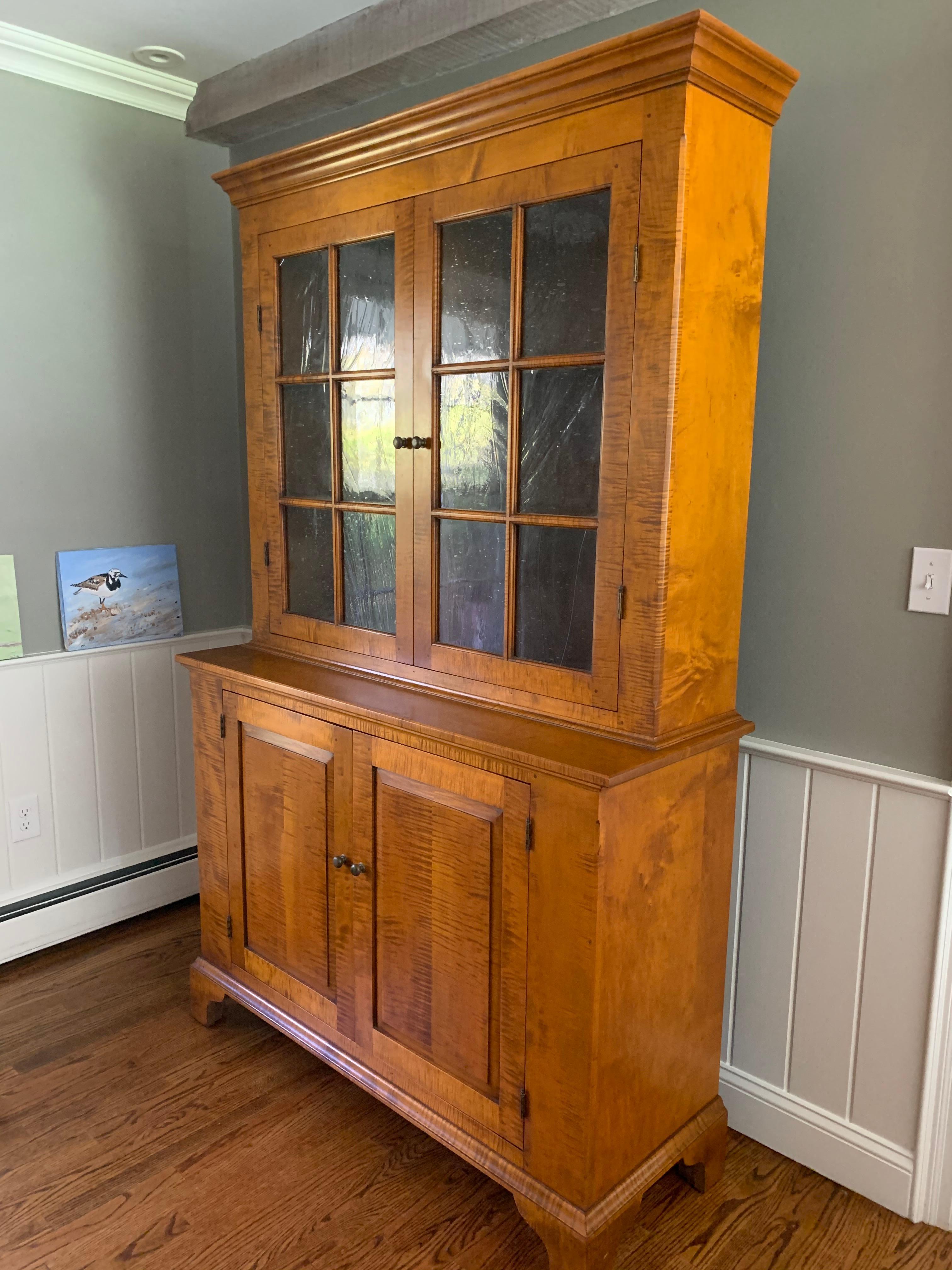 Very handsome solid artisan handmade tiger maple china cabinet have two doors on top with seeded glass, and 2 panel doors on the bottom. Offers lots of storage.
  